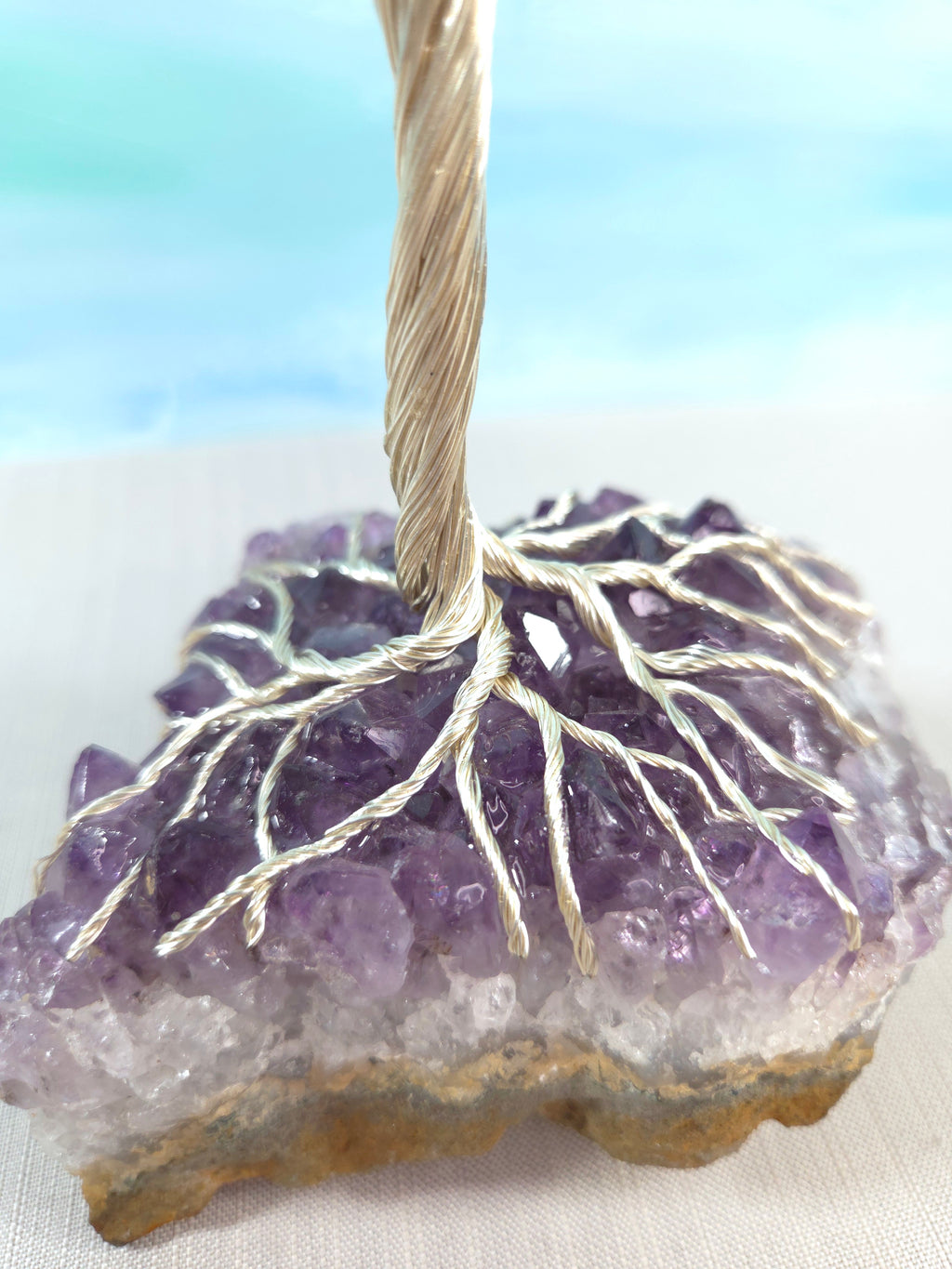 Amethyst crystal with silver wire wrapped around it on a light background