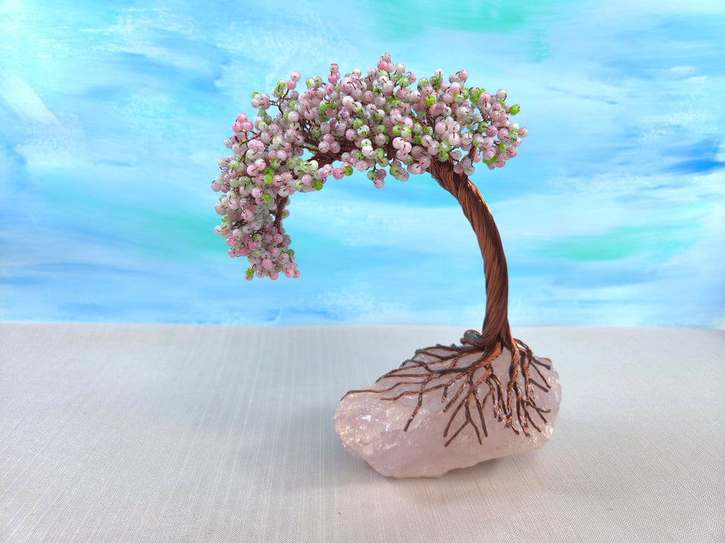 Decorative bonsai tree on a crystal base with a blurred blue and green background