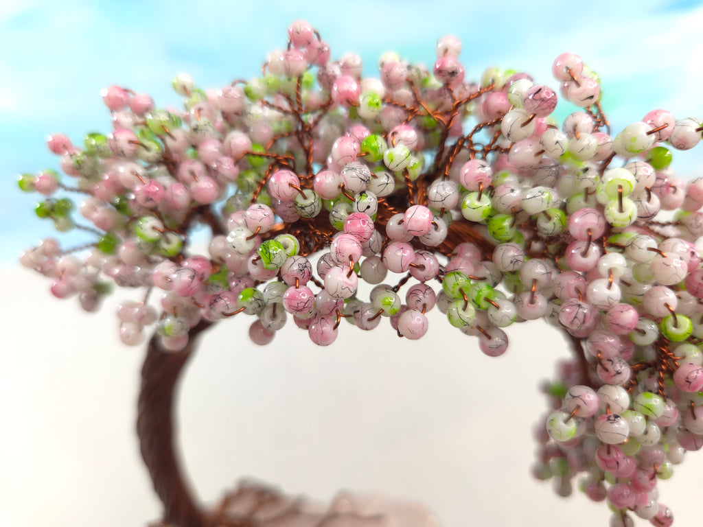 Artificial bonsai tree with pink and green berries against a light blue sky