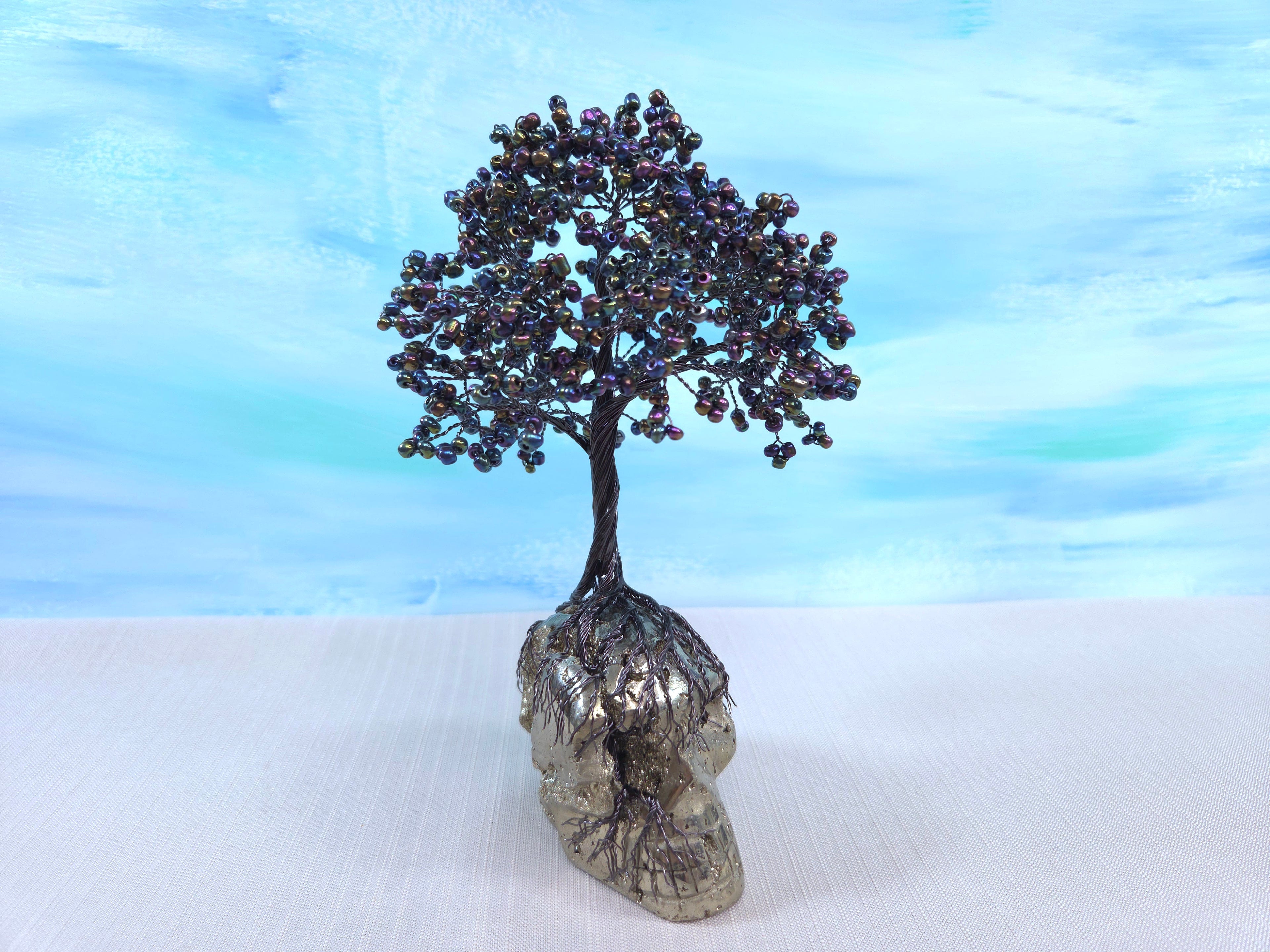 Decorative tree made of beads on a rock with a blue gradient background