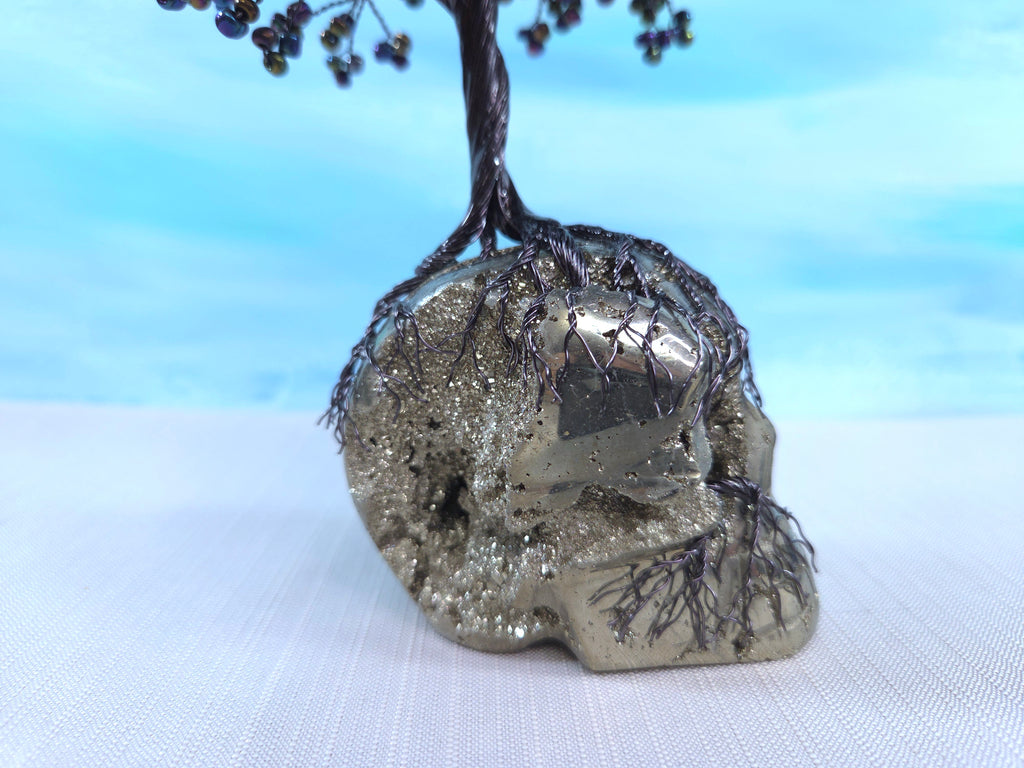 Decorative crystal skull with a tree on a white surface and blue gradient background