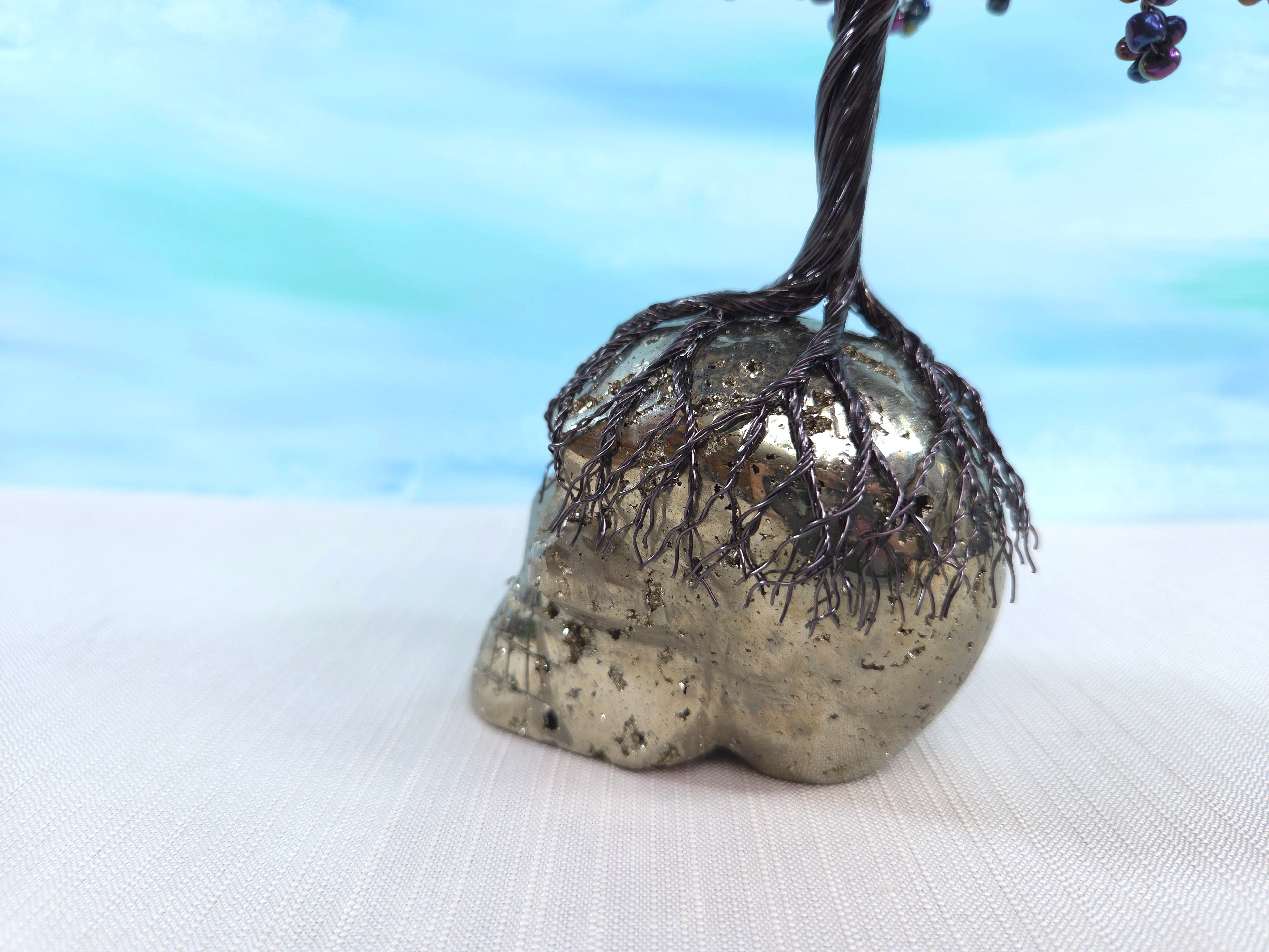 Decorative object resembling a tree with metallic trunk on a white surface