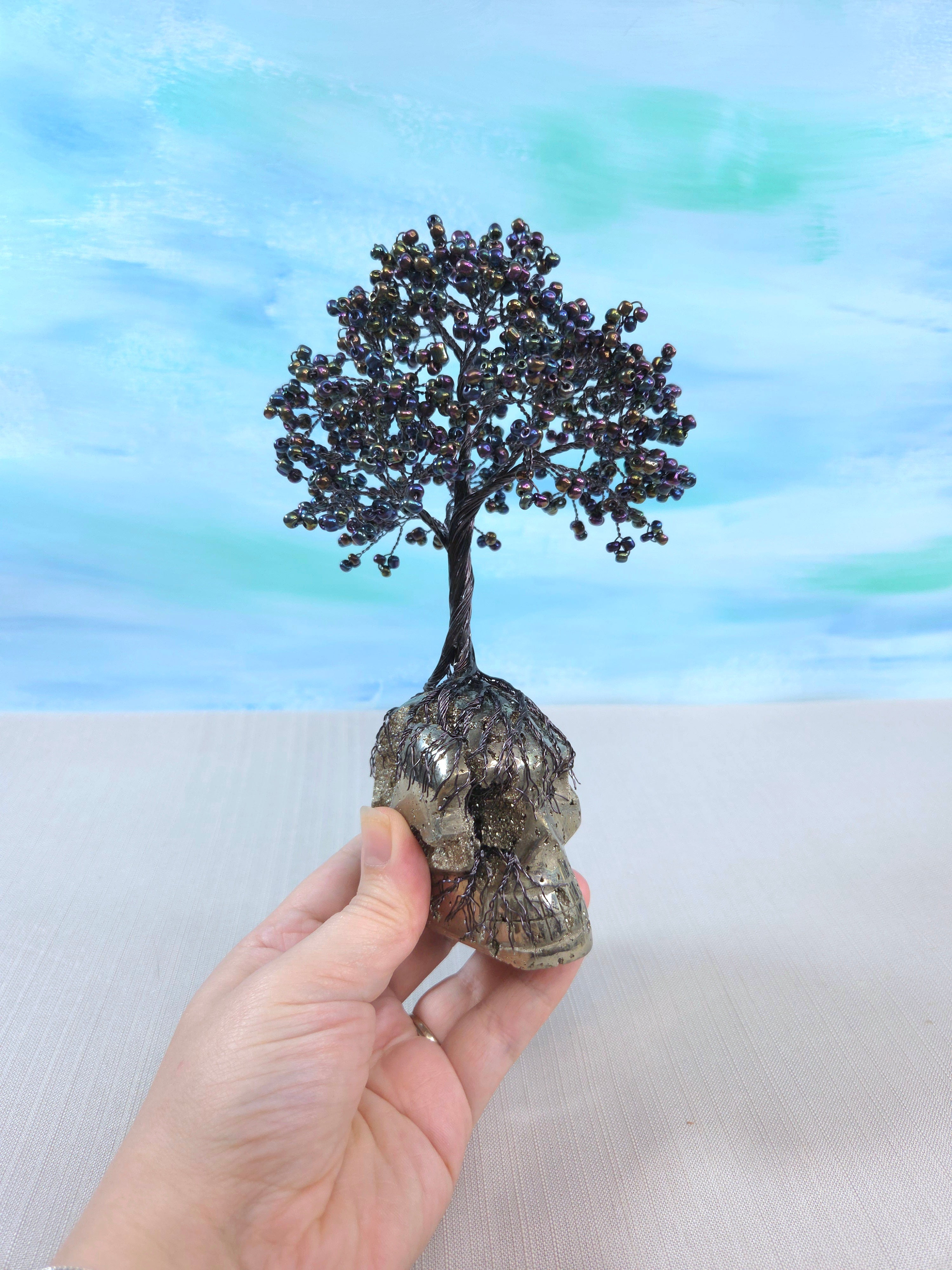 Decorative tree on a crystal base held by a hand with a colorful background