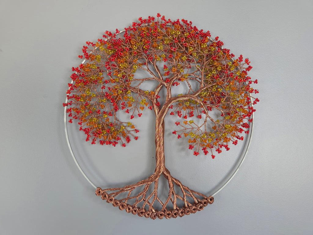 Decorative wall art of a tree with red and orange leaves on a gray background