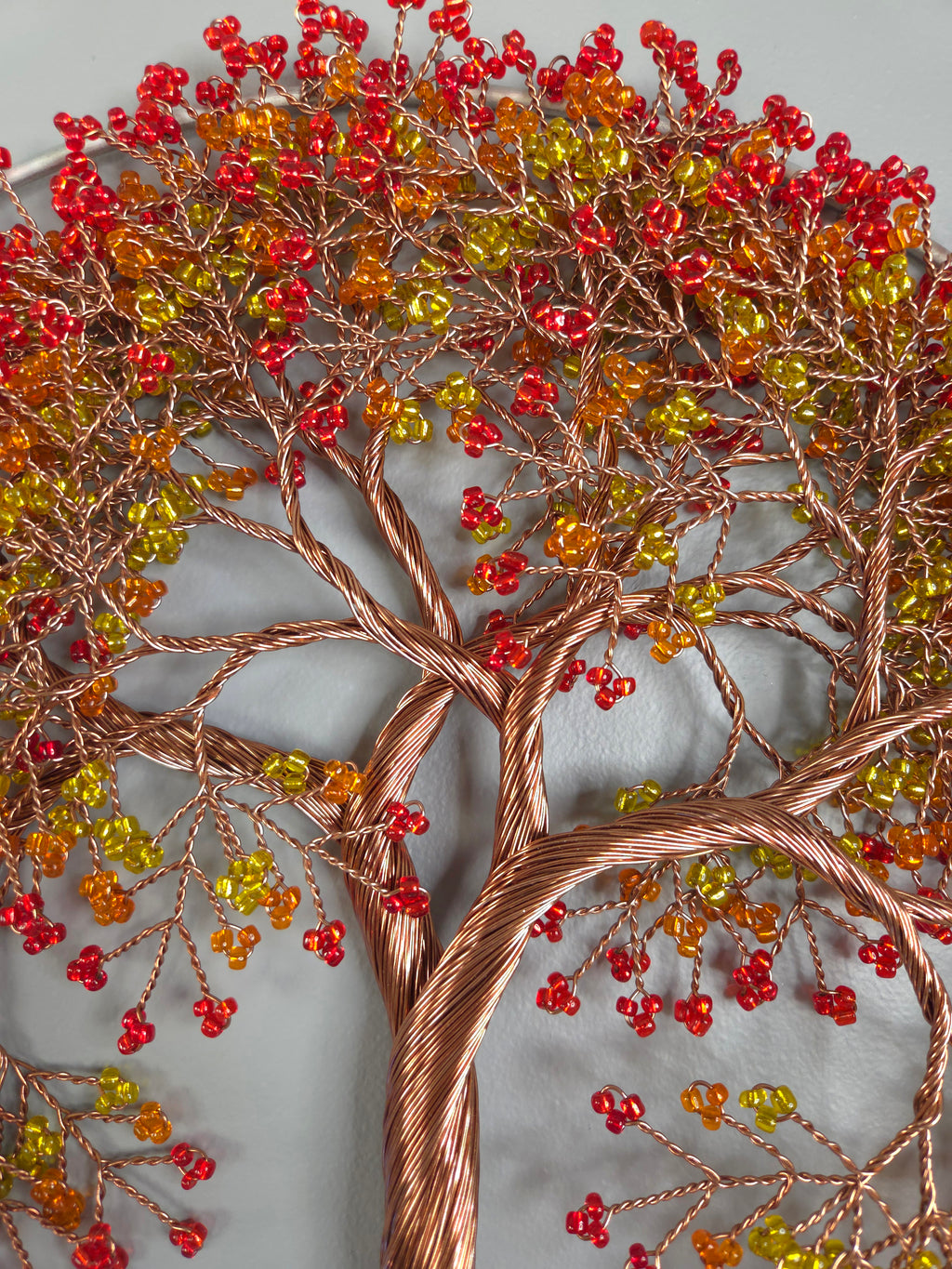 Decorative wall art of a tree with red and yellow berries on a gray background