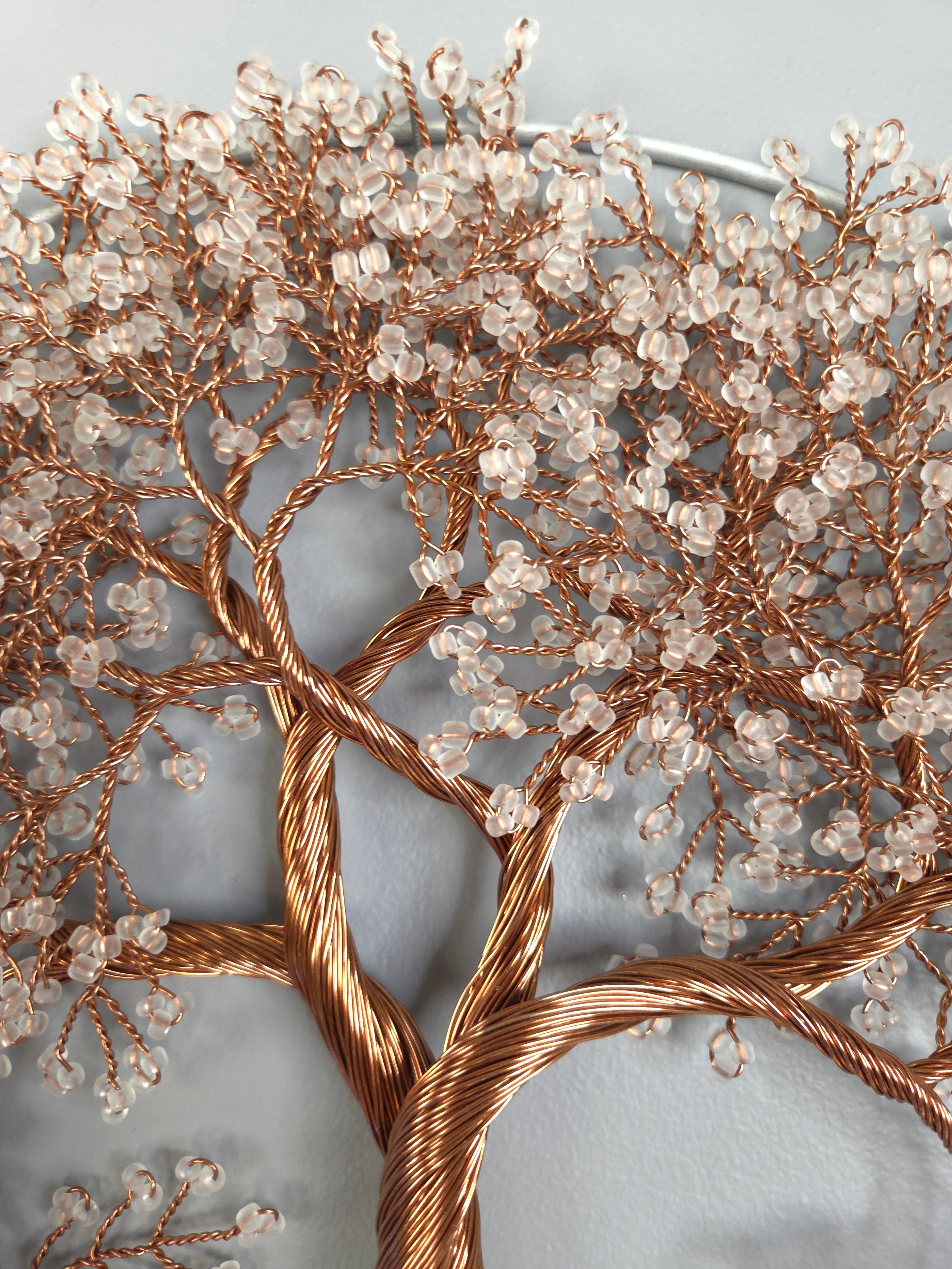 Decorative wall art of a tree with copper branches and clear beads on a light gray background