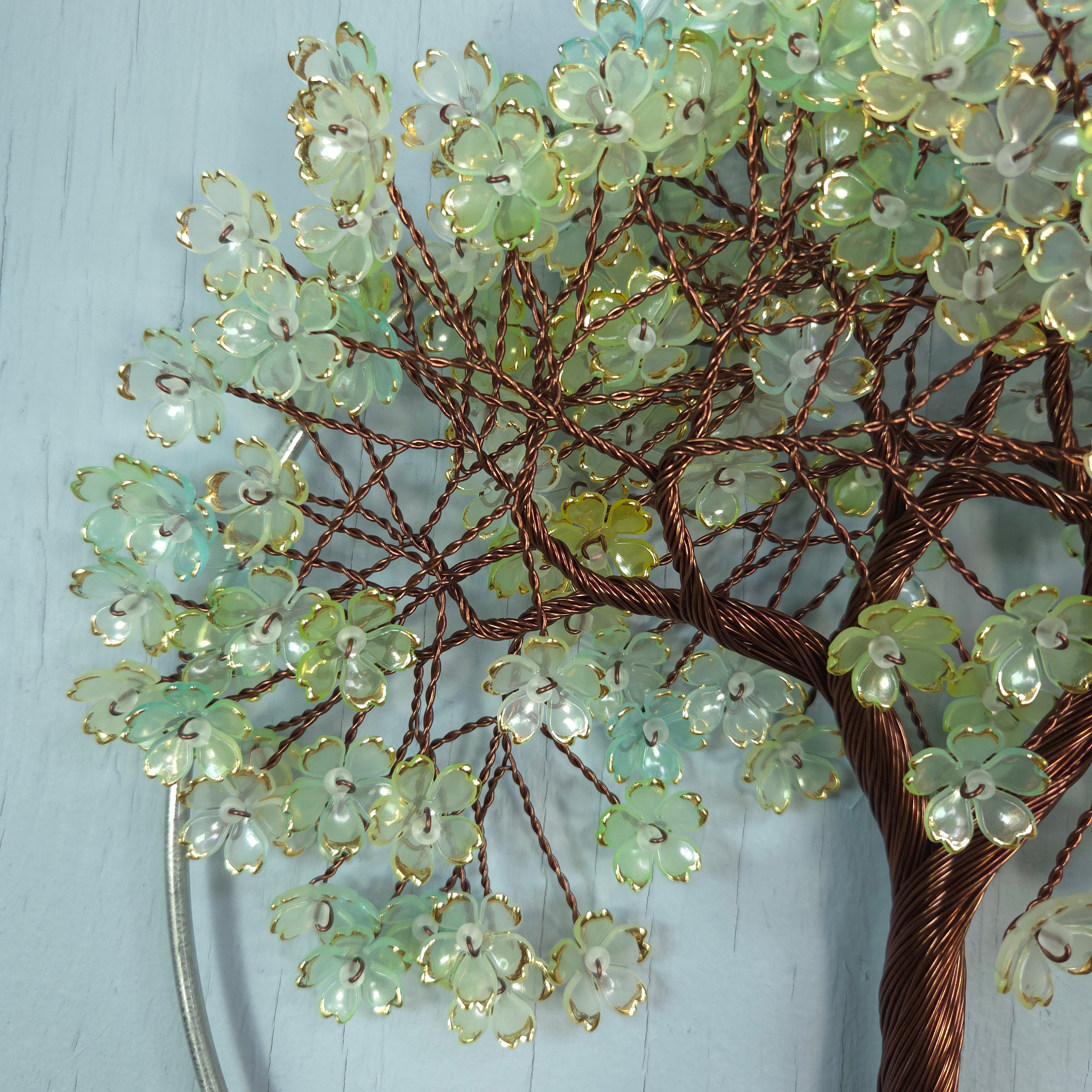 Decorative branch with green floral beads on a light blue background