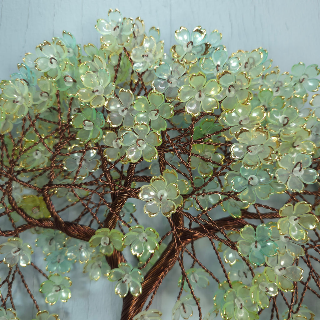 Decorative branch with green flowers on a light blue background