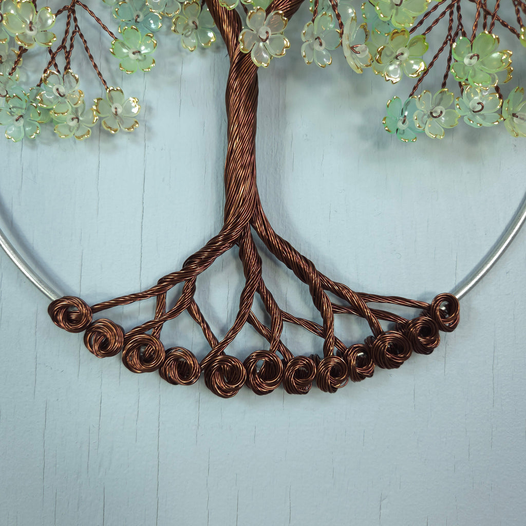 Decorative wreath with brown wire branches and green floral elements on a light blue background