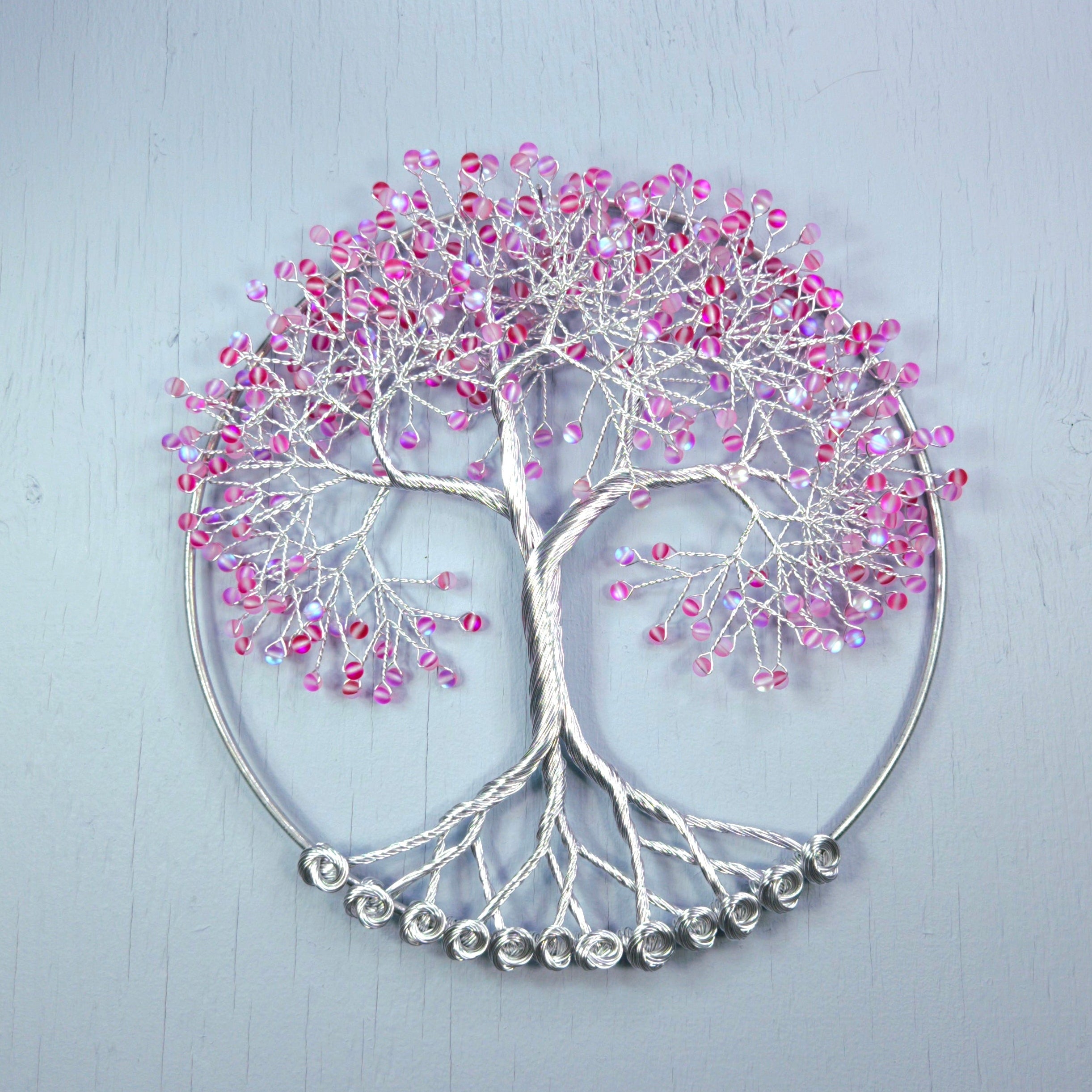 Decorative wall art with pink and silver tree design on a light gray background