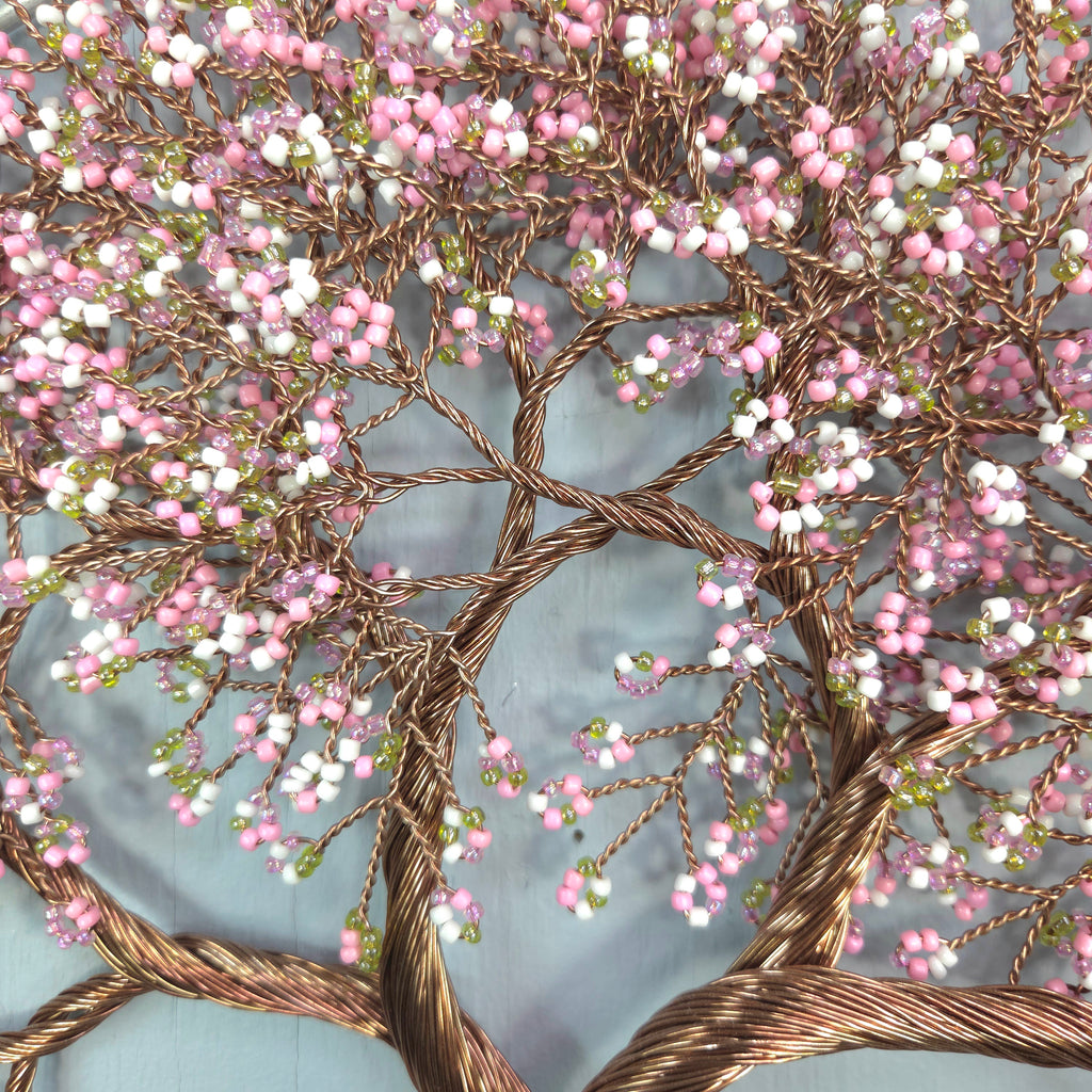 Decorative tree sculpture with pink and white beads on a light blue background