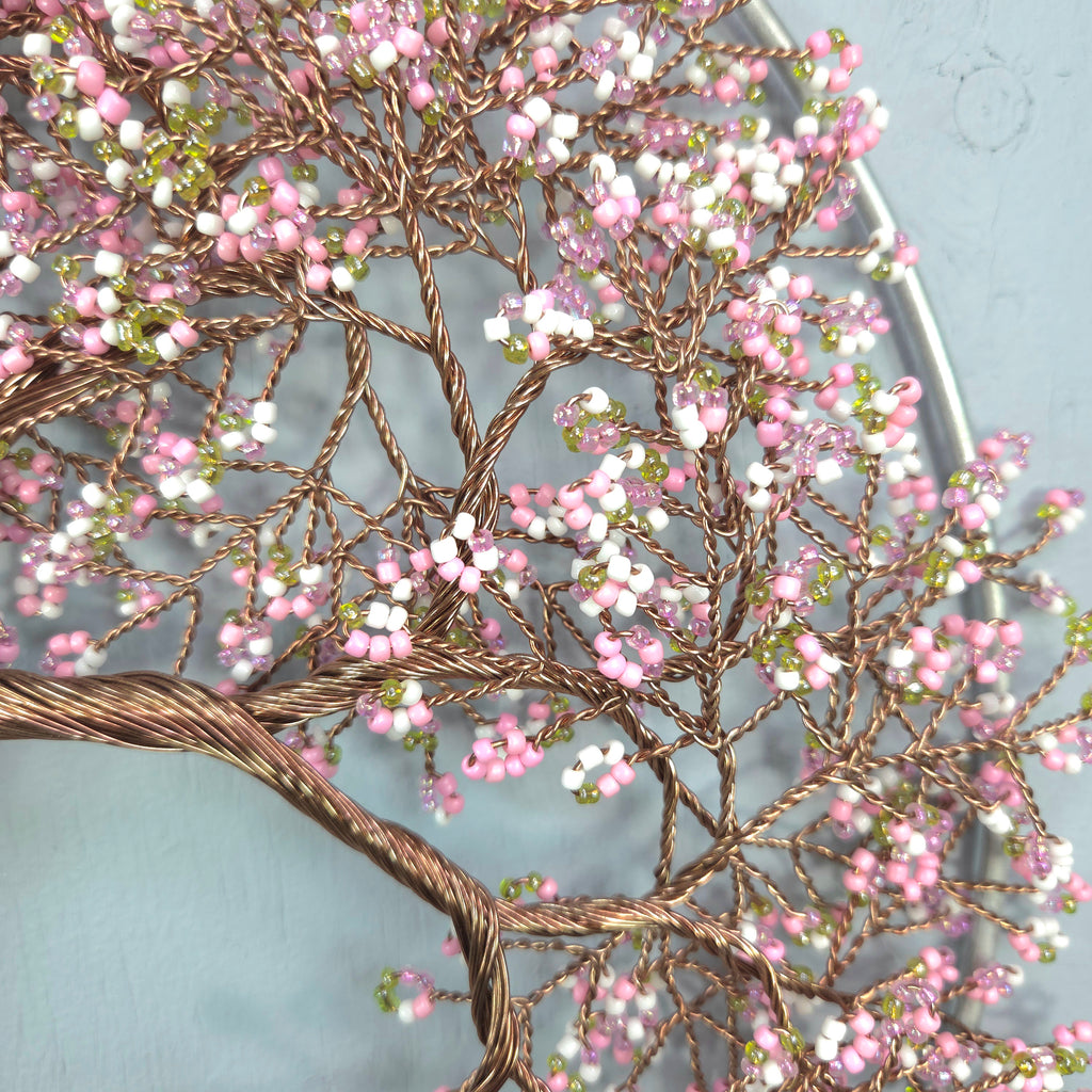 Decorative tree sculpture with pink and white beads on a light blue background