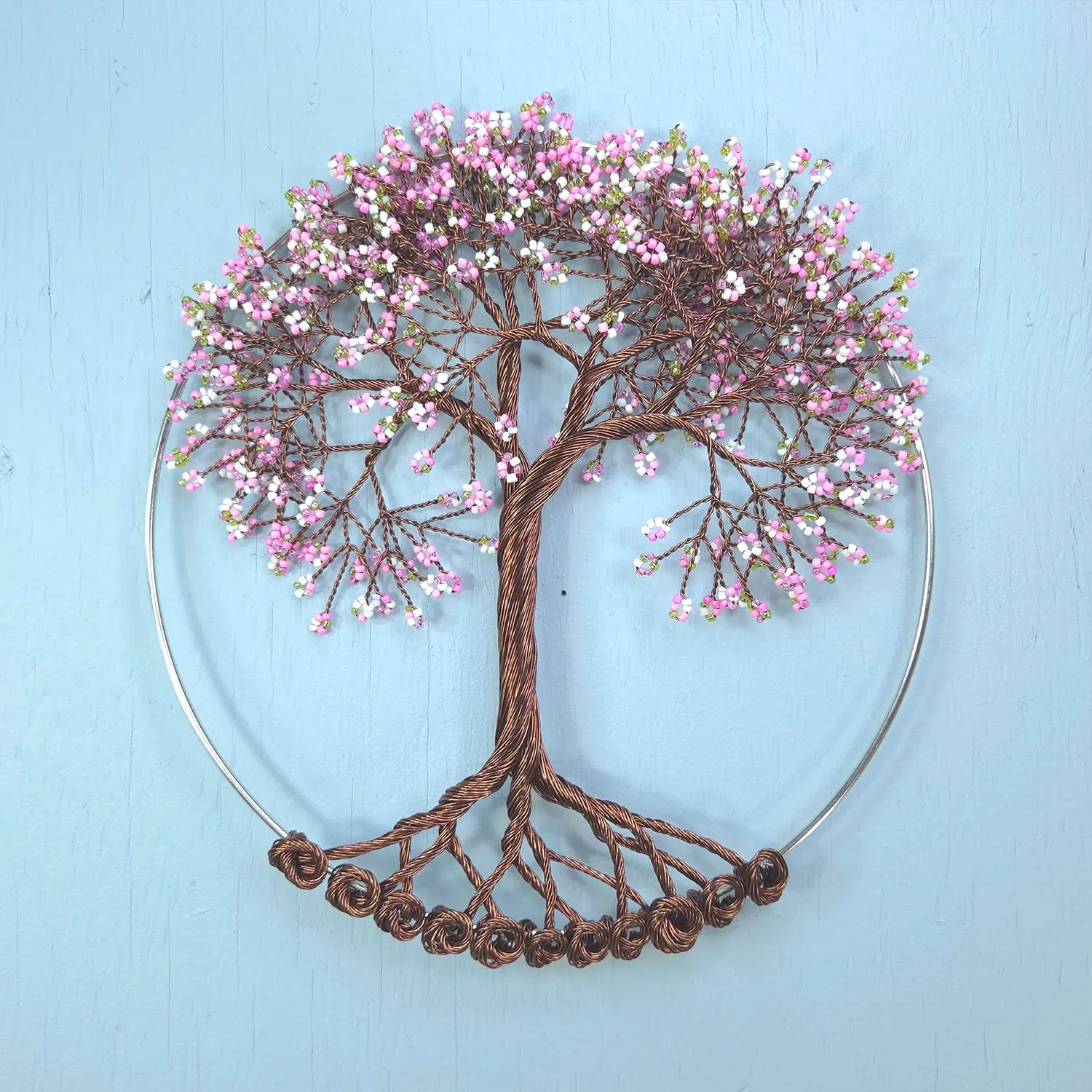 Decorative wall art of a tree with pink flowers on a light blue background