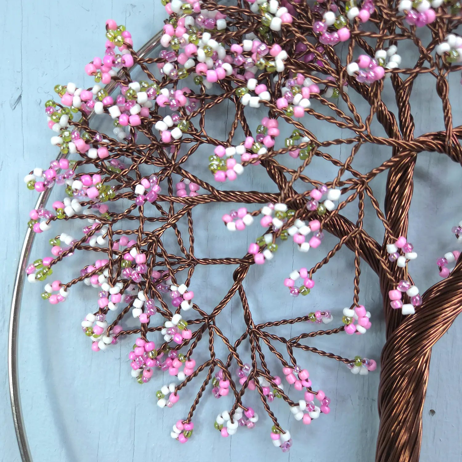 Decorative wall art of a tree with pink and white beads on a blue background
