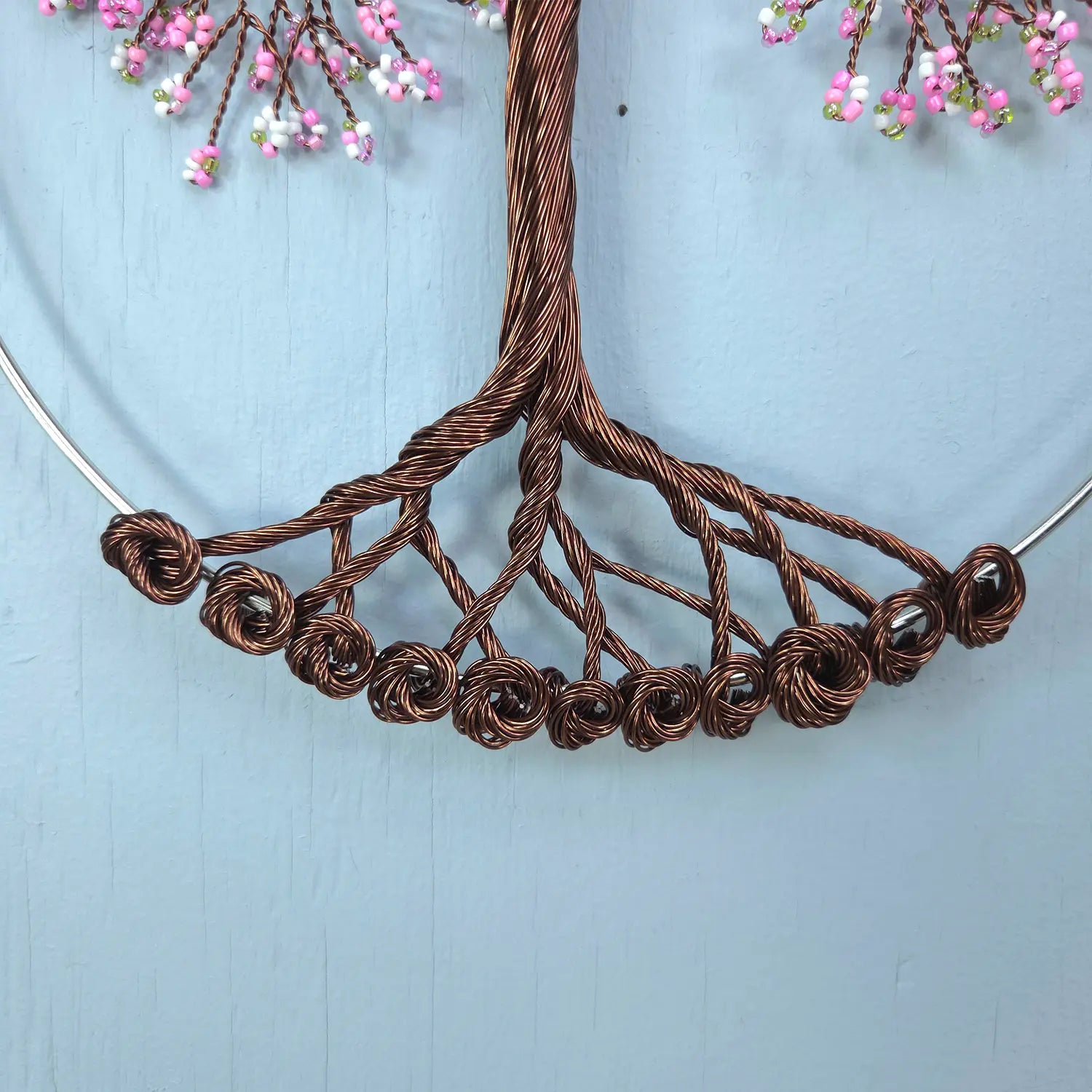 Brown wire necklace with decorative elements on a light blue background