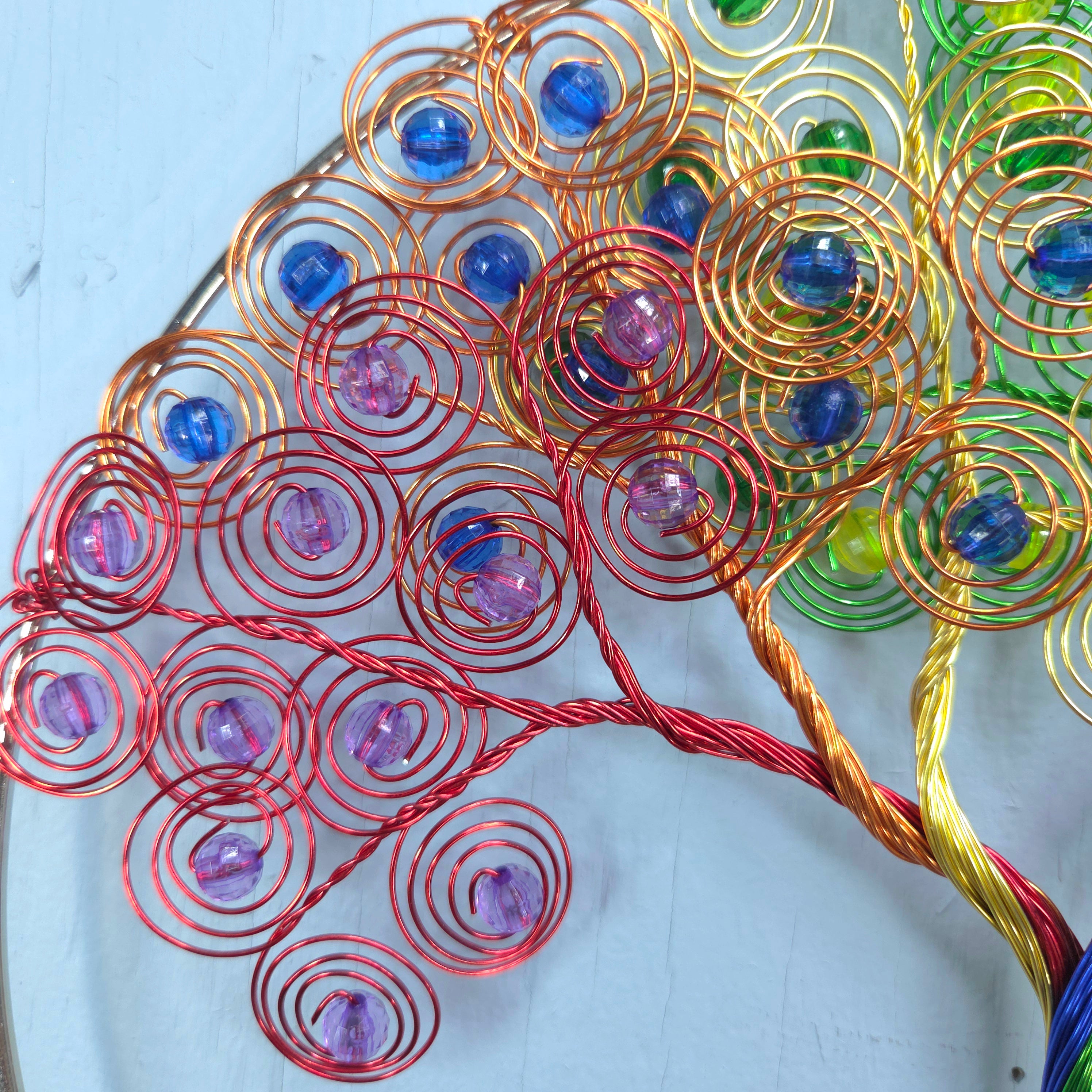 Colorful wire tree sculpture with beads on a light blue background