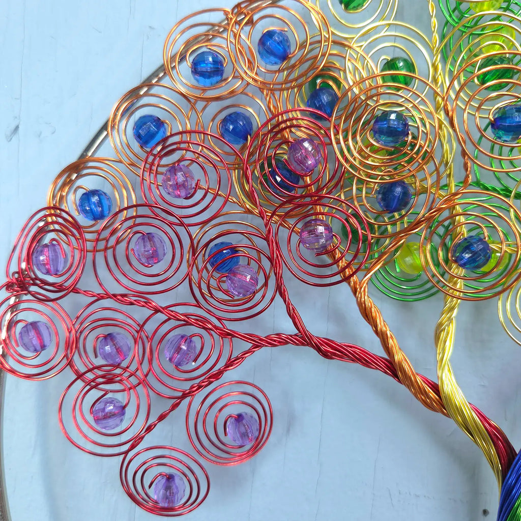 Colorful wire tree sculpture with beads on a light blue background