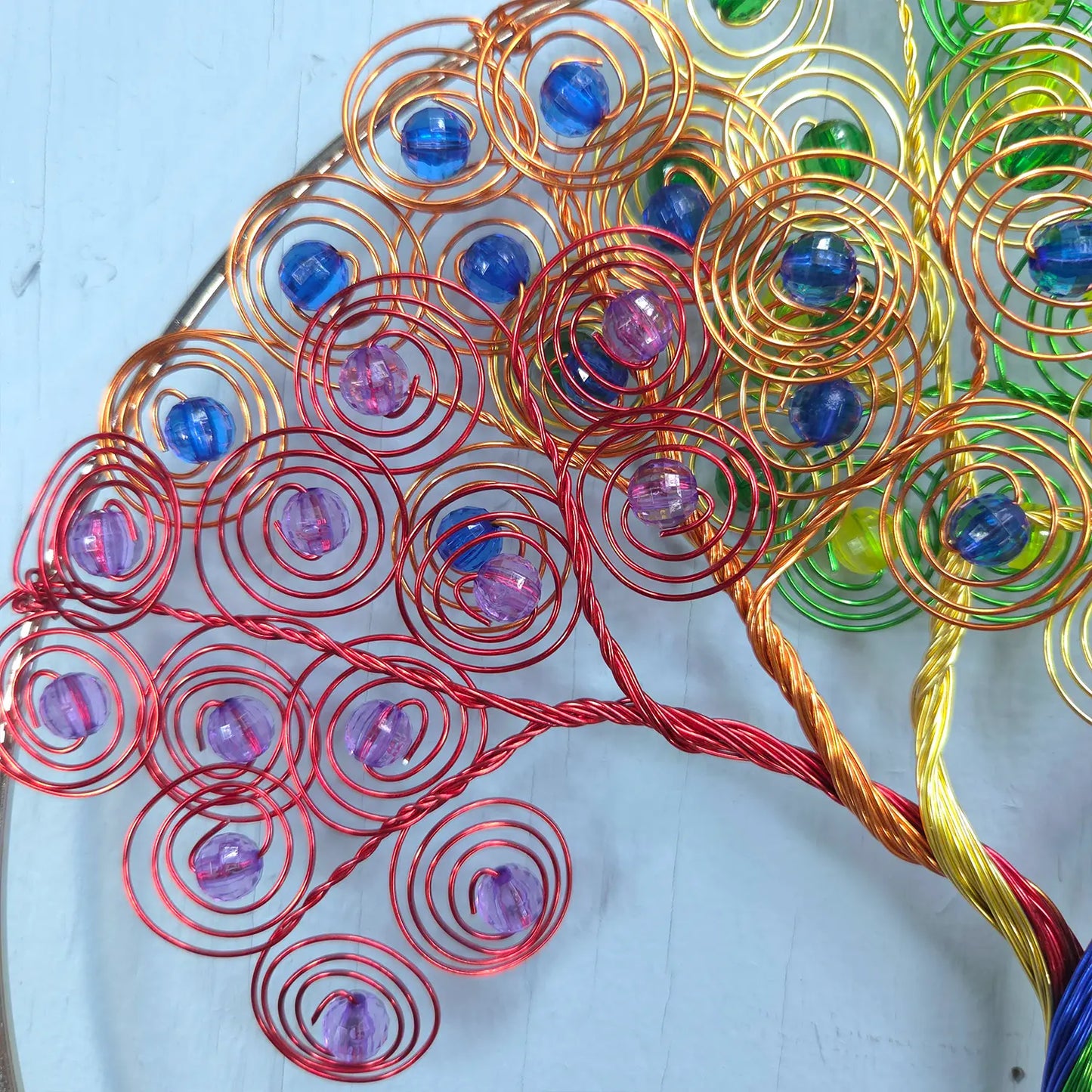 Colorful wire tree sculpture with beads on a light blue background