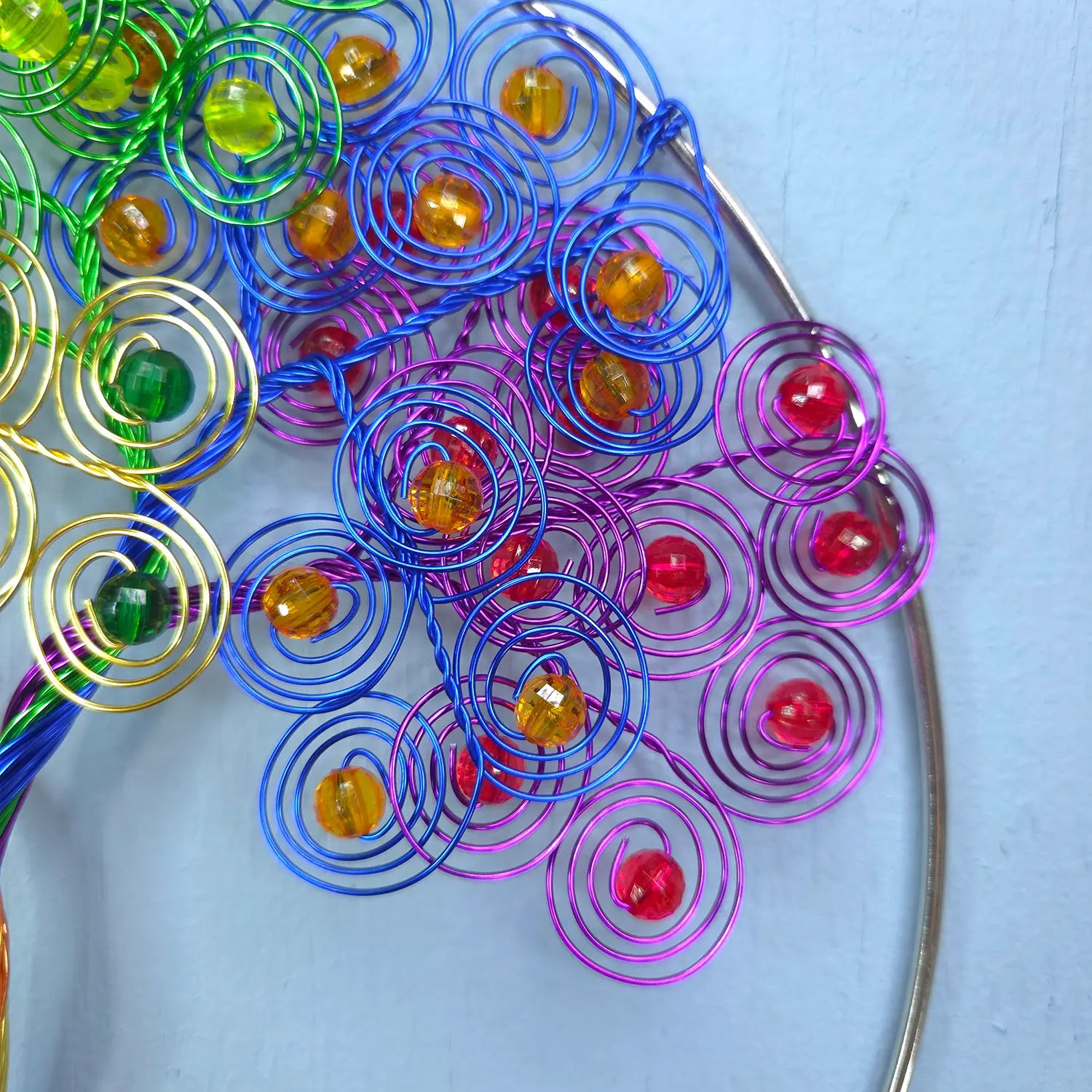 Colorful metal spiral decorations with beads on a light blue background
