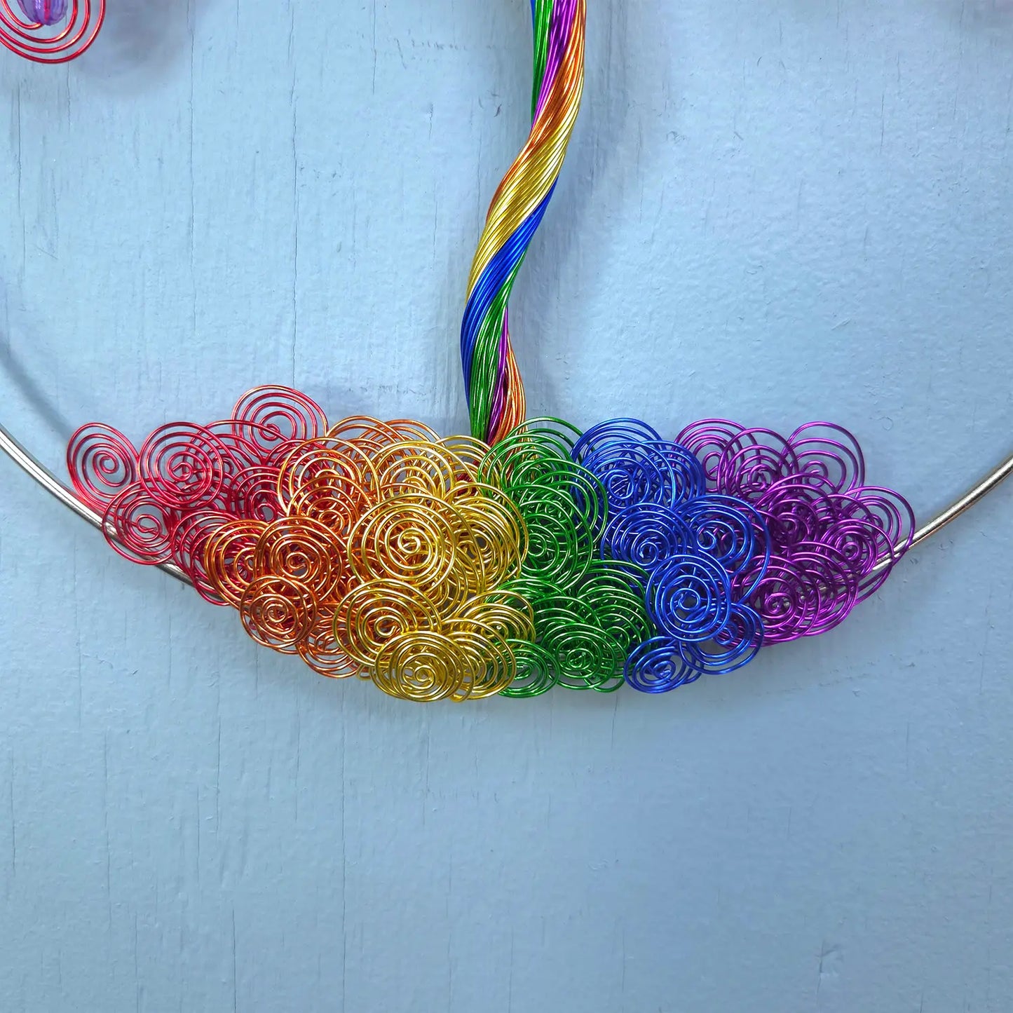 Necklace with rainbow-colored wire loops on a light blue background