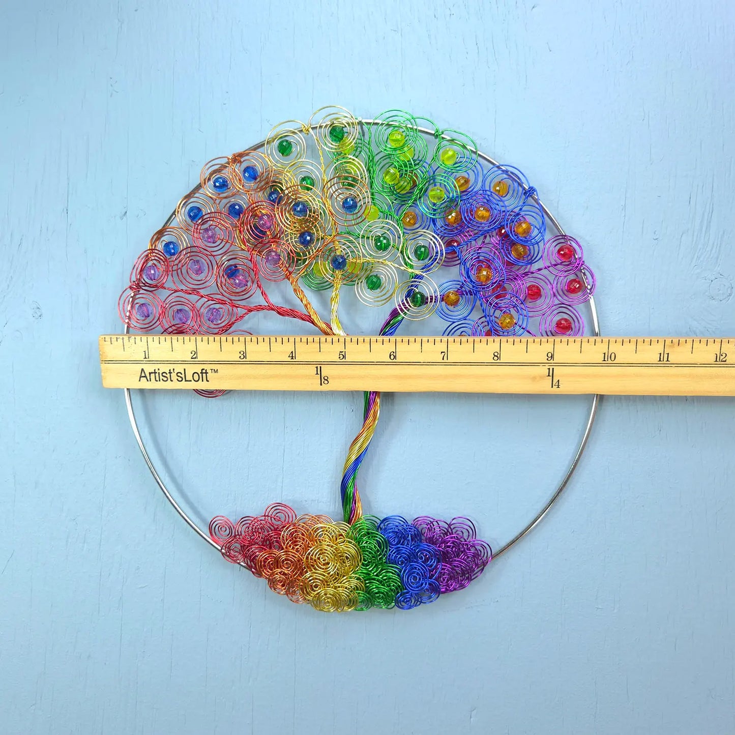 Colorful beaded fan with a ruler for scale on a light blue background