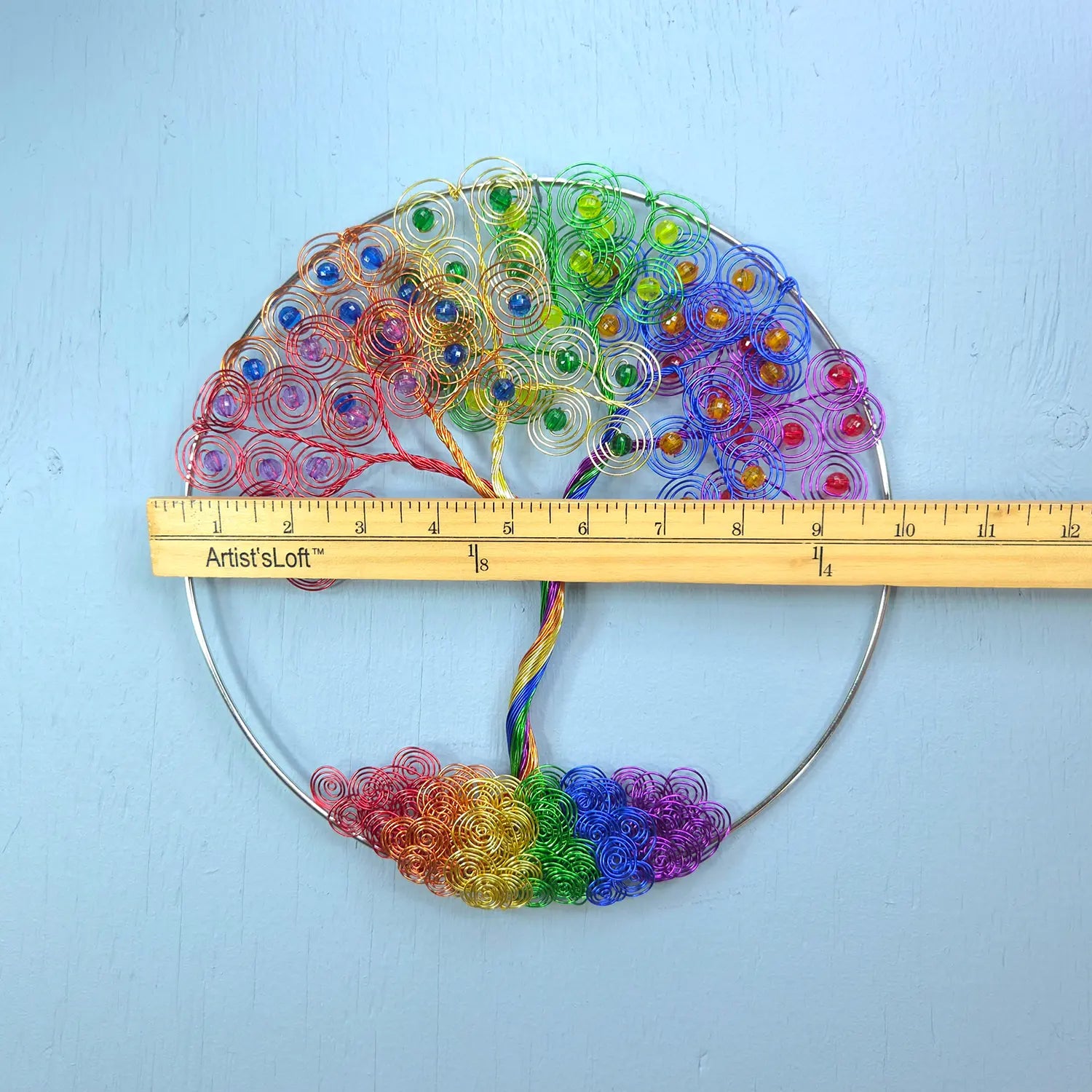Colorful beaded fan with a ruler for scale on a light blue background