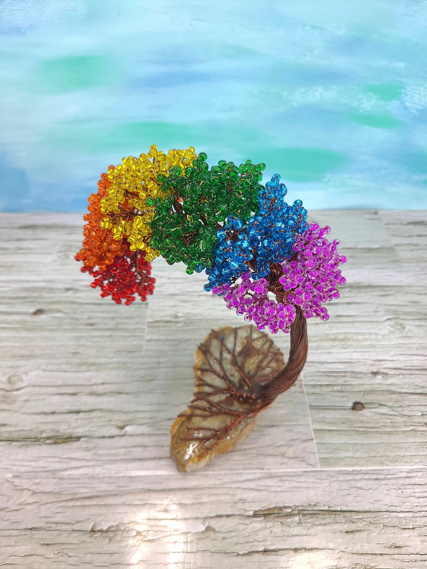 Colorful beaded tree on a wooden surface with a blurred natural background