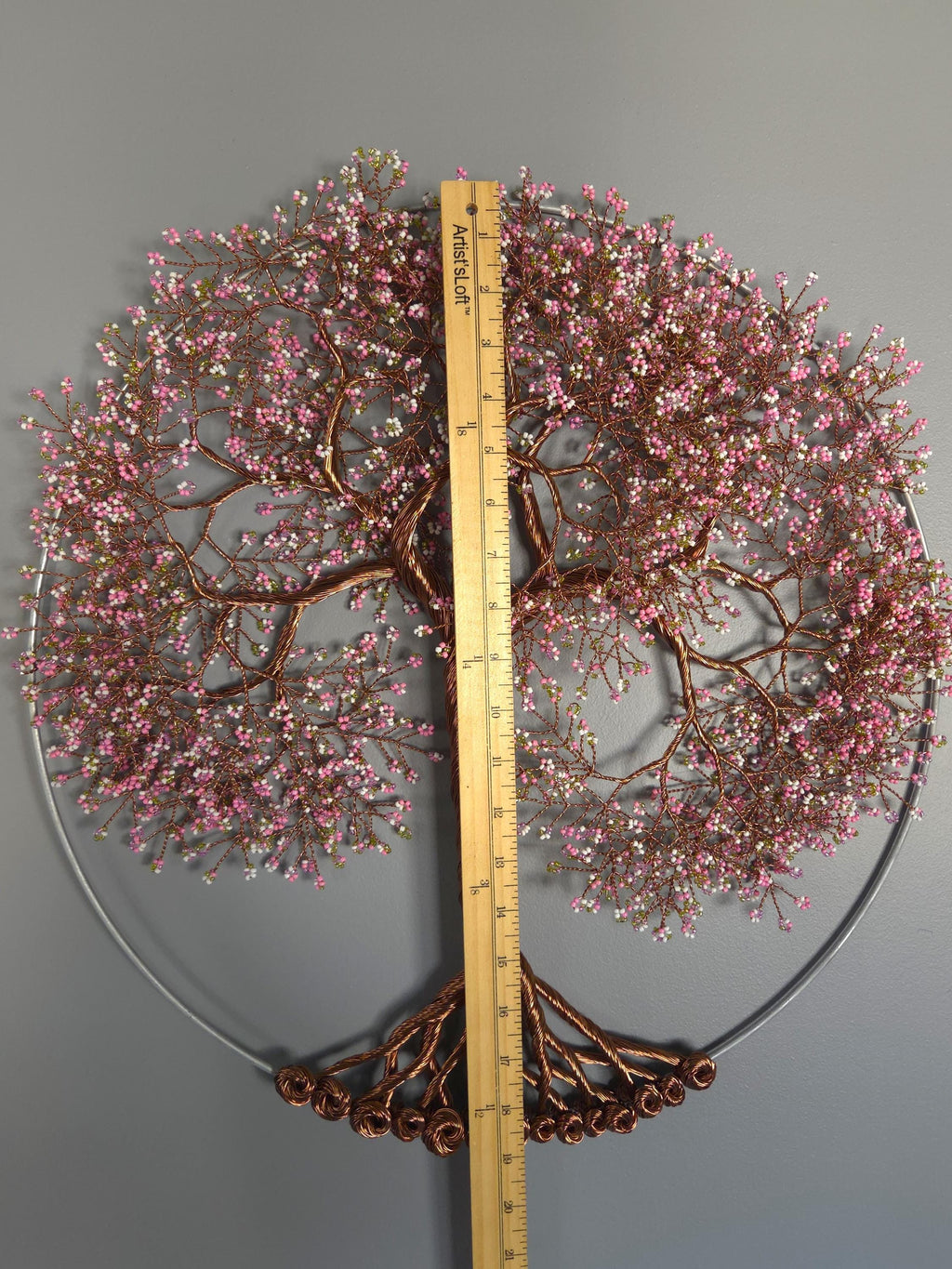 Decorative wall piece with pink and brown branches on a gray background