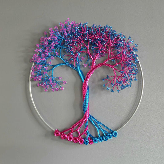Decorative wall art in the shape of a tree with pink and blue branches on a gray background