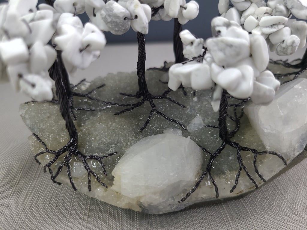 Decorative stone arch with white stones and black wire, on a gray surface.