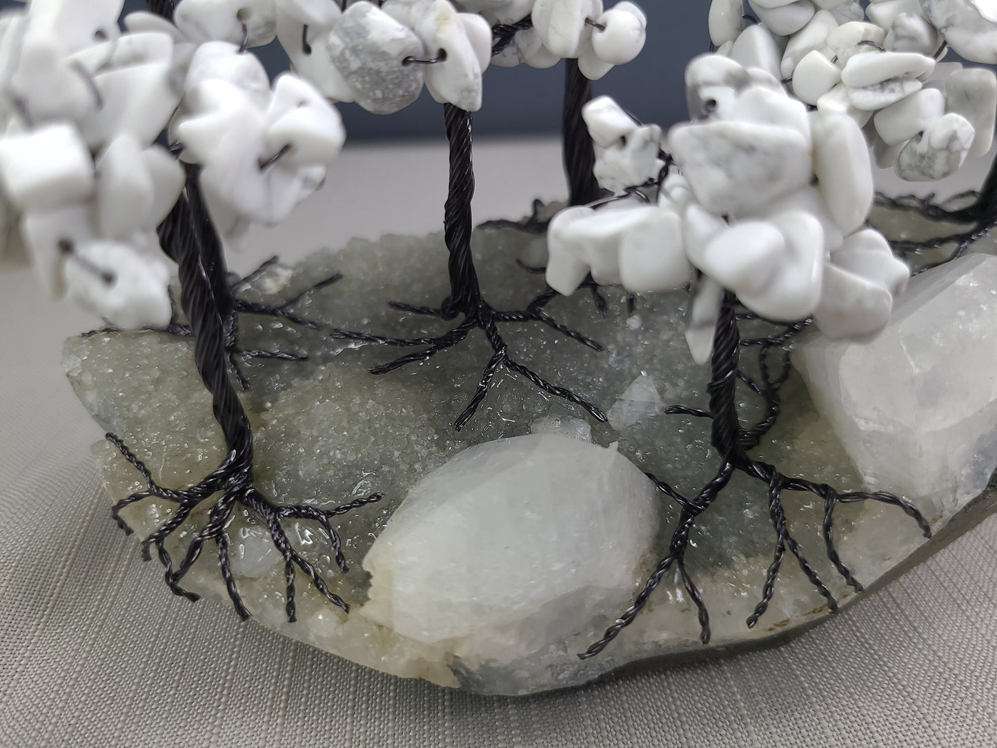 Decorative stone arch with white stones and black wire, on a gray surface.