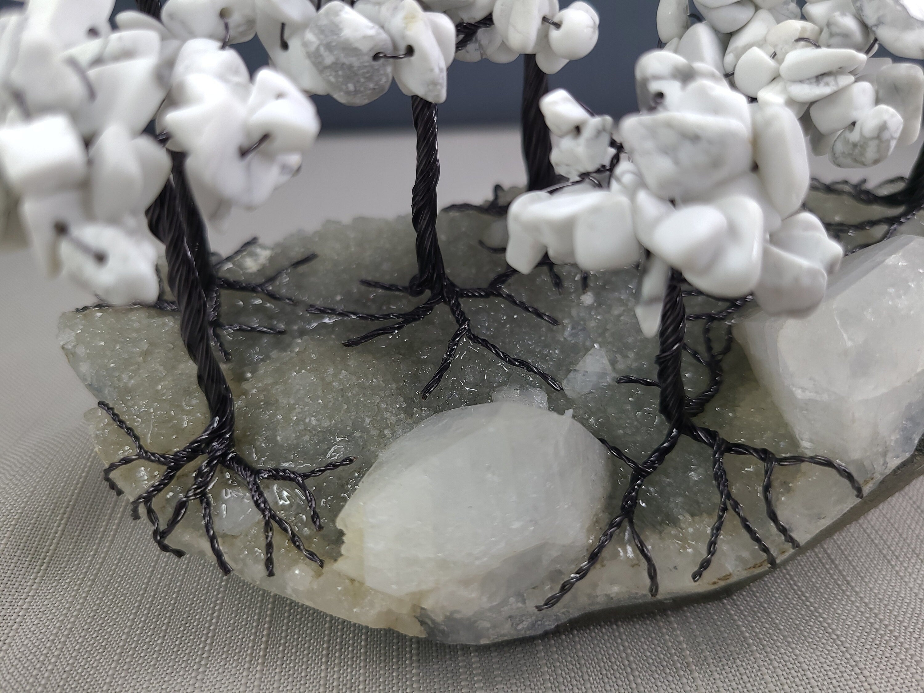 Decorative stone arch with white stones and black wire, on a gray surface.