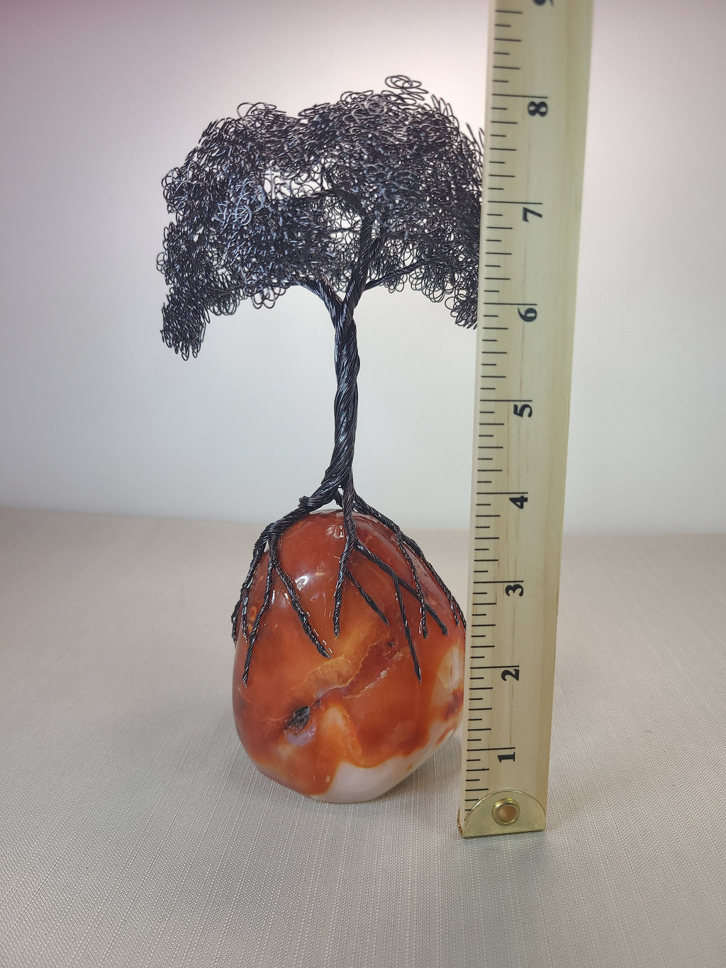 Decorative tree sculpture on a stone base with a ruler for scale.