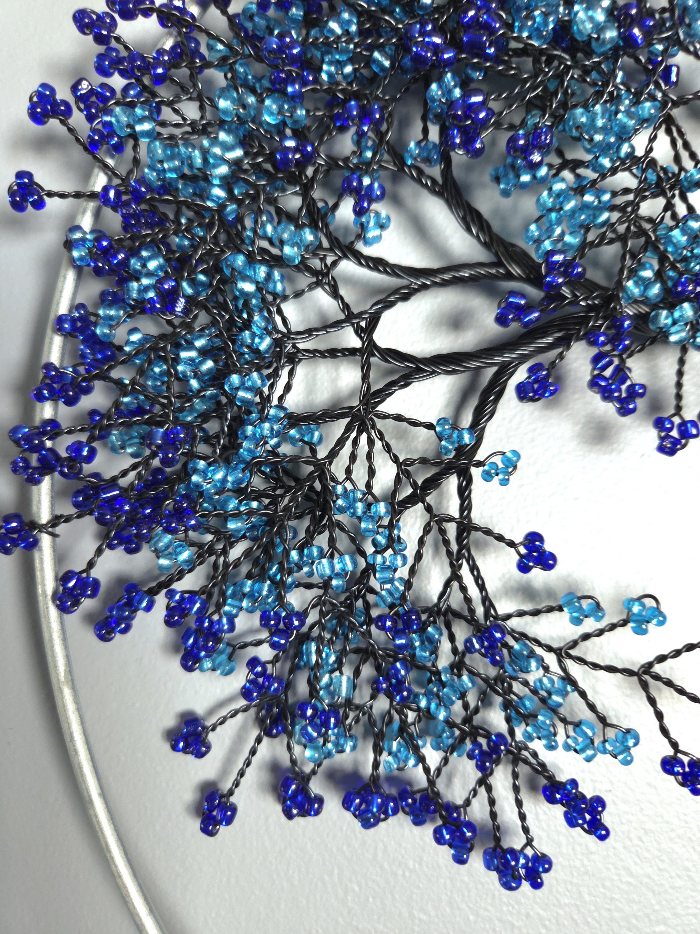 Decorative branch with blue and black beads on a white background