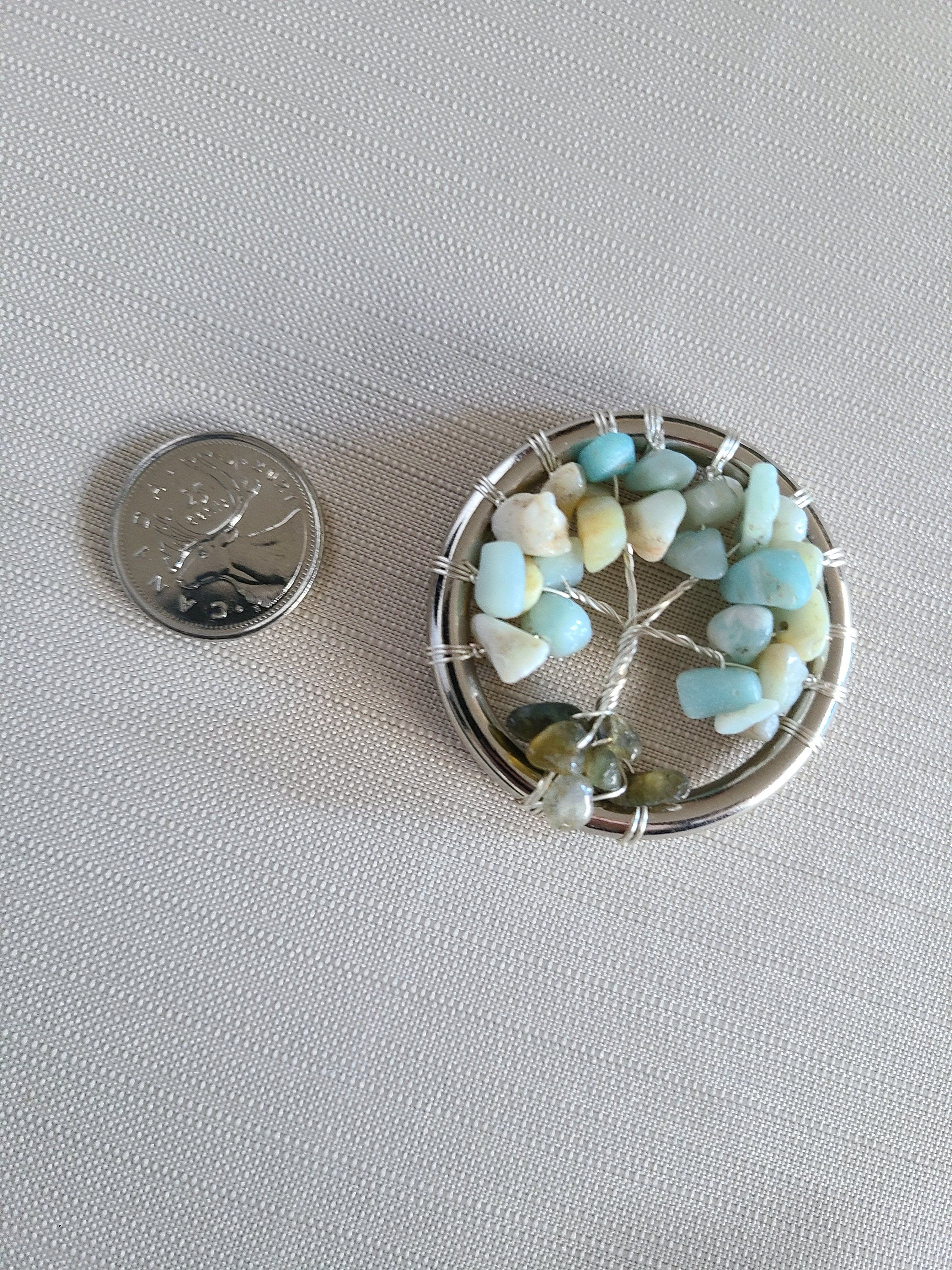 Small circular decorative item with stones next to a quarter on a light gray background