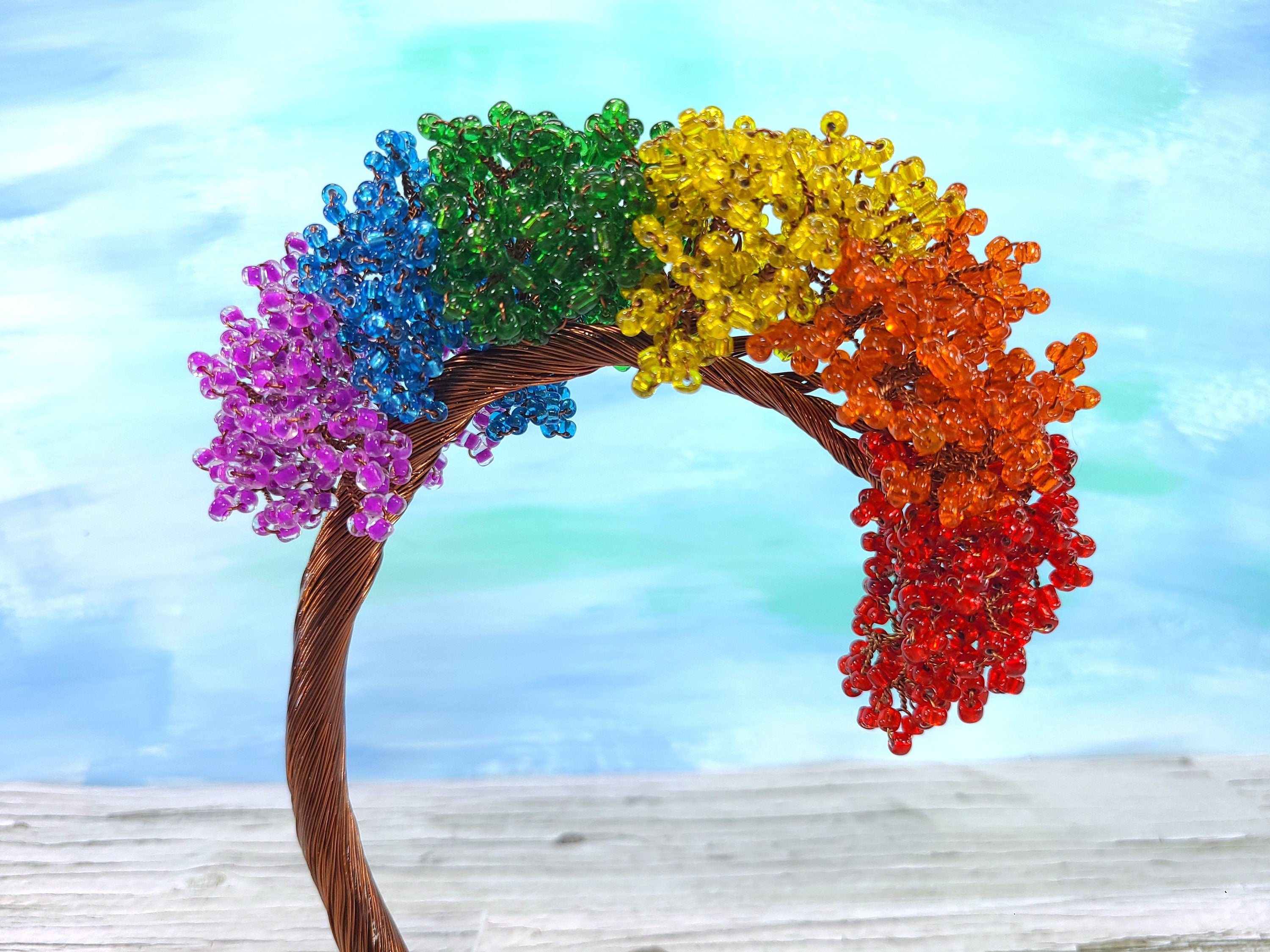 Colorful beaded arch with a rainbow pattern on a wooden surface and light blue background