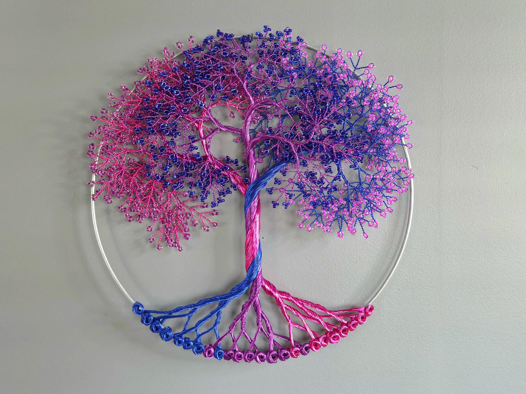 Decorative wall art of a tree with pink and blue branches on a light gray background