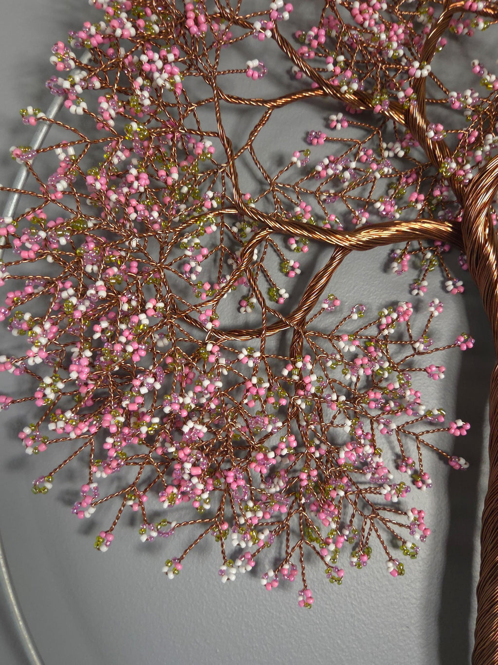 Decorative wall piece with pink and white berries on a gray background