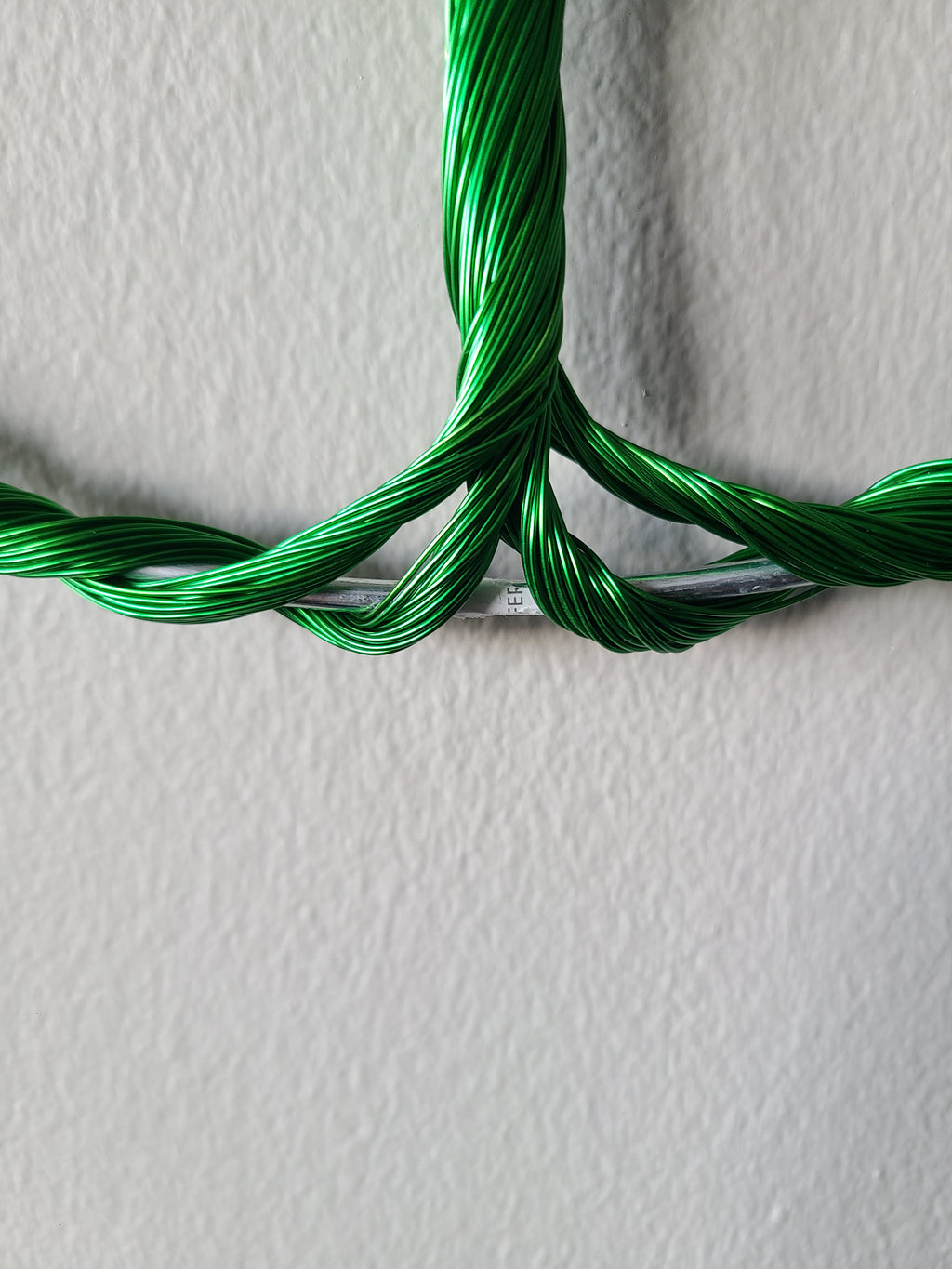 Green braided cable on a textured white background