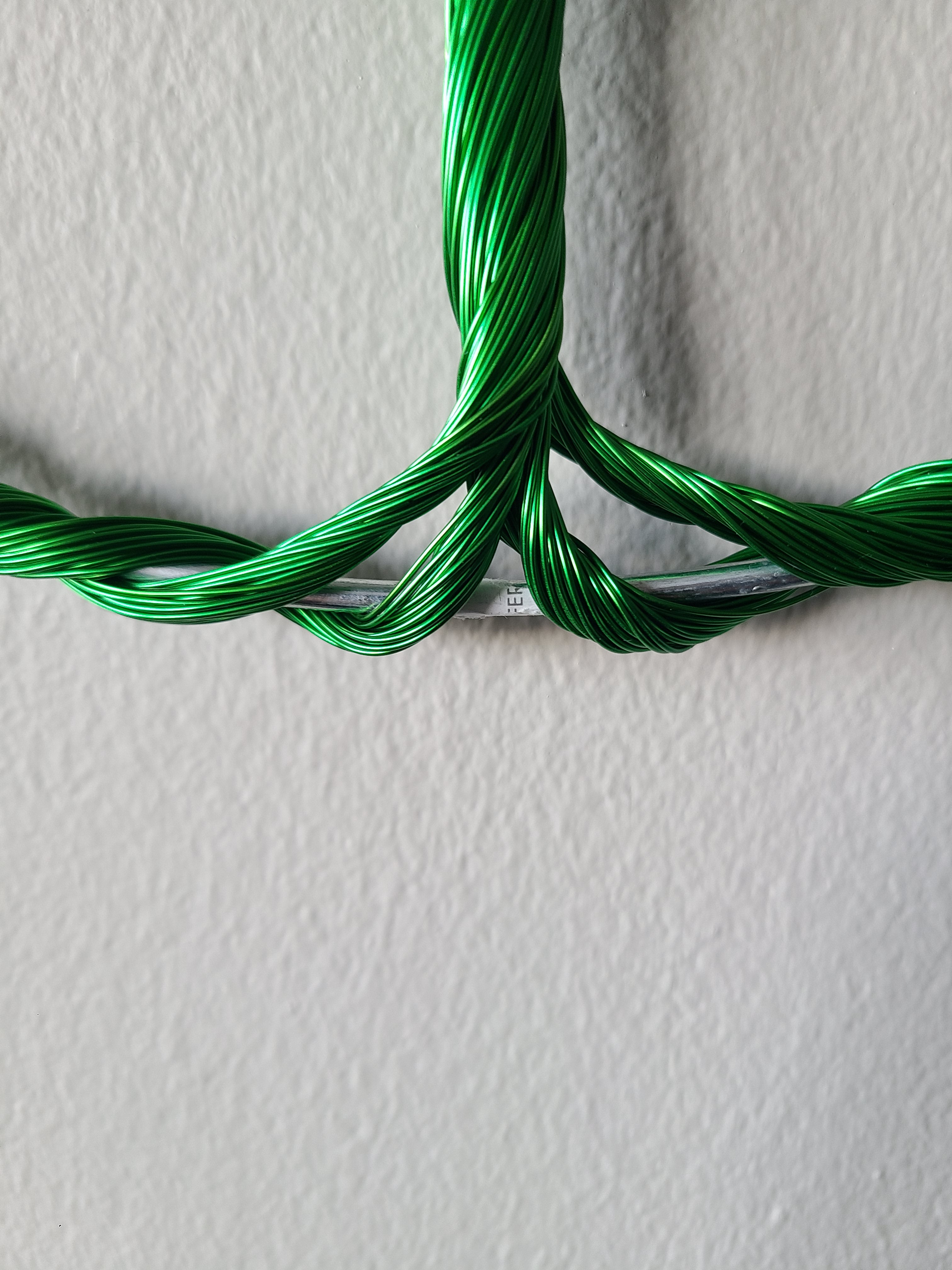 Green braided cable on a textured white background