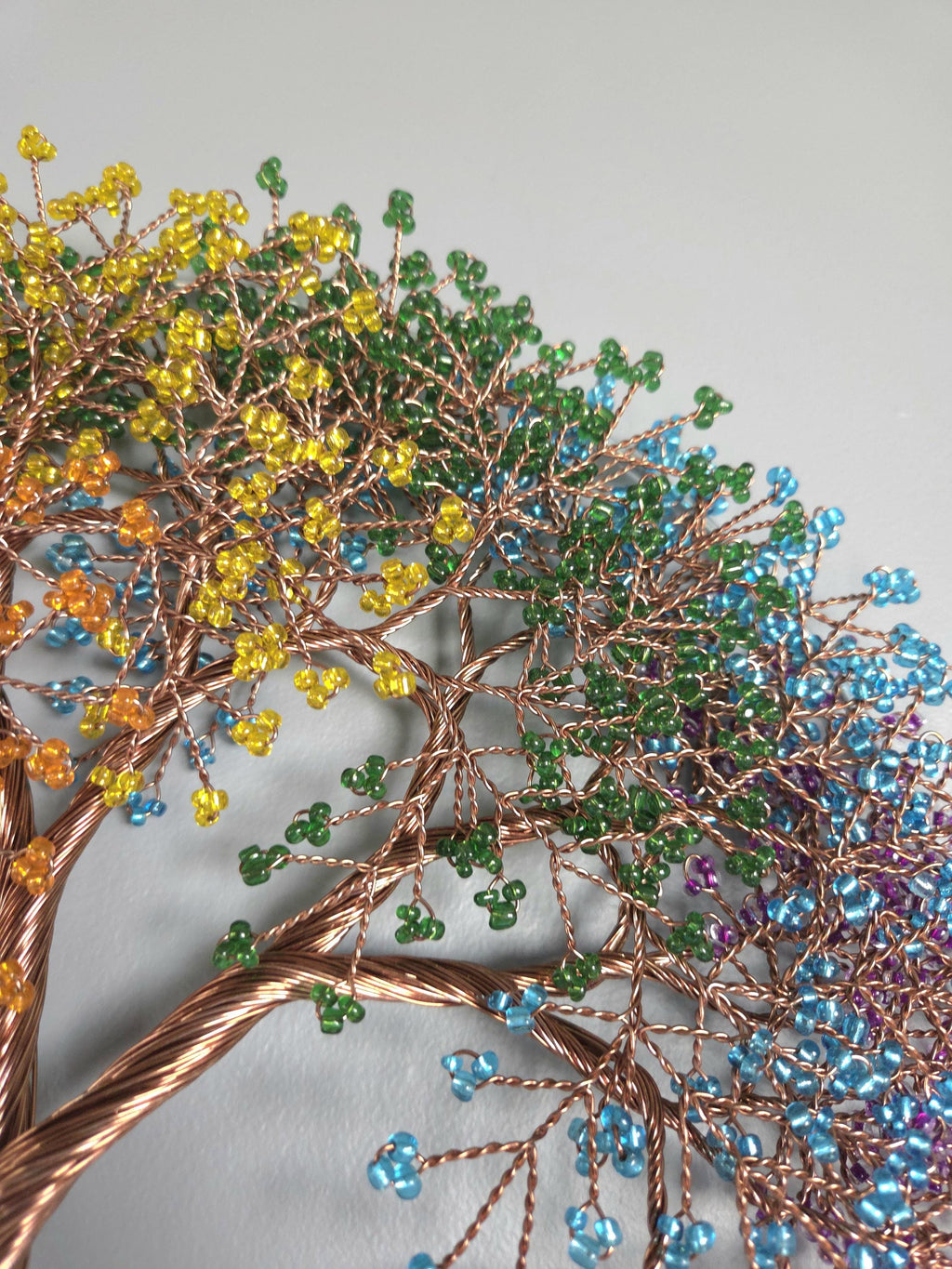 Decorative tree sculpture with colorful beads on a light gray background