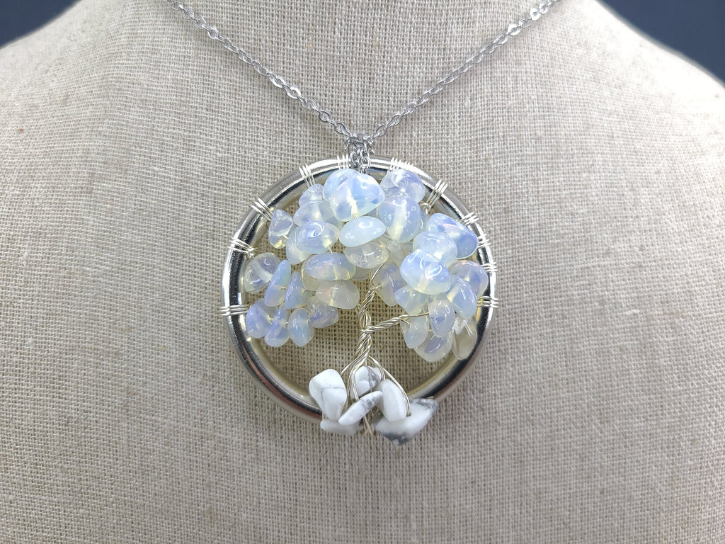 Silver necklace with a circular pendant featuring blue and white stones on a gray mannequin.