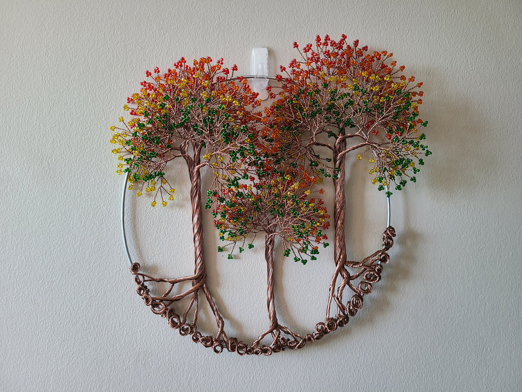 Decorative wall art of intertwined trees with autumn foliage on a plain wall.