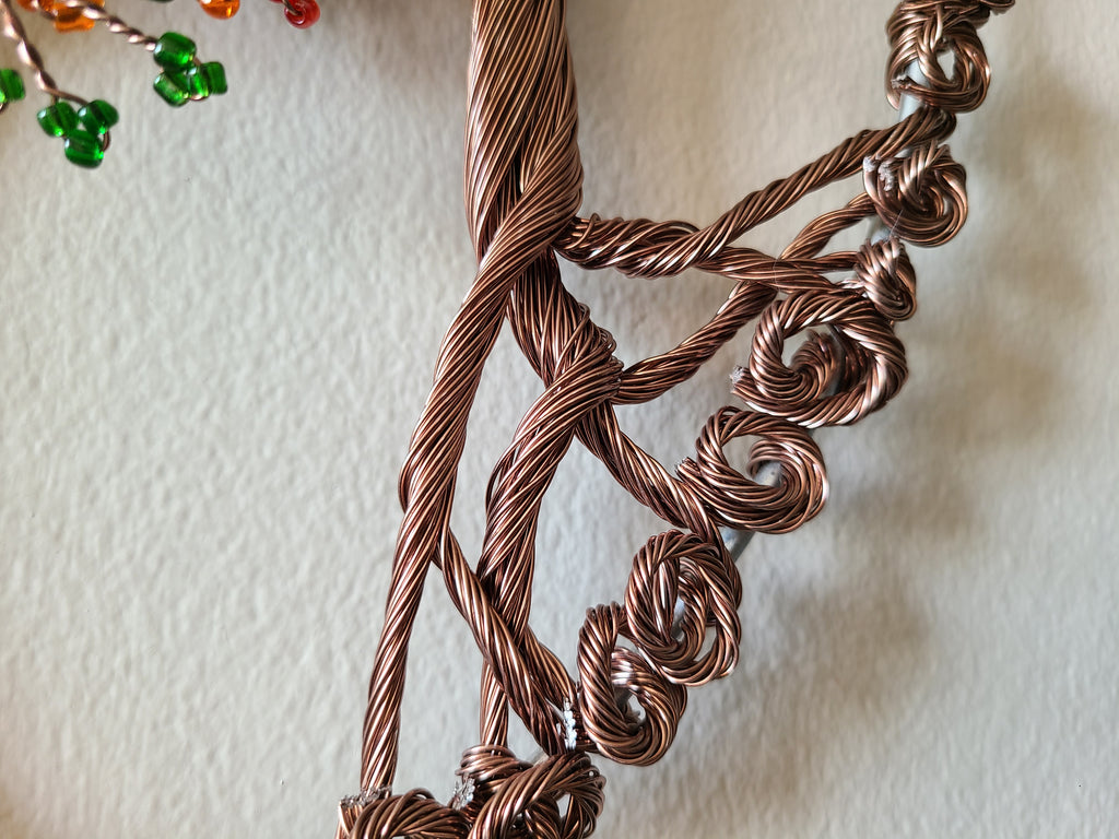 Close-up of a braided copper necklace on a textured beige background