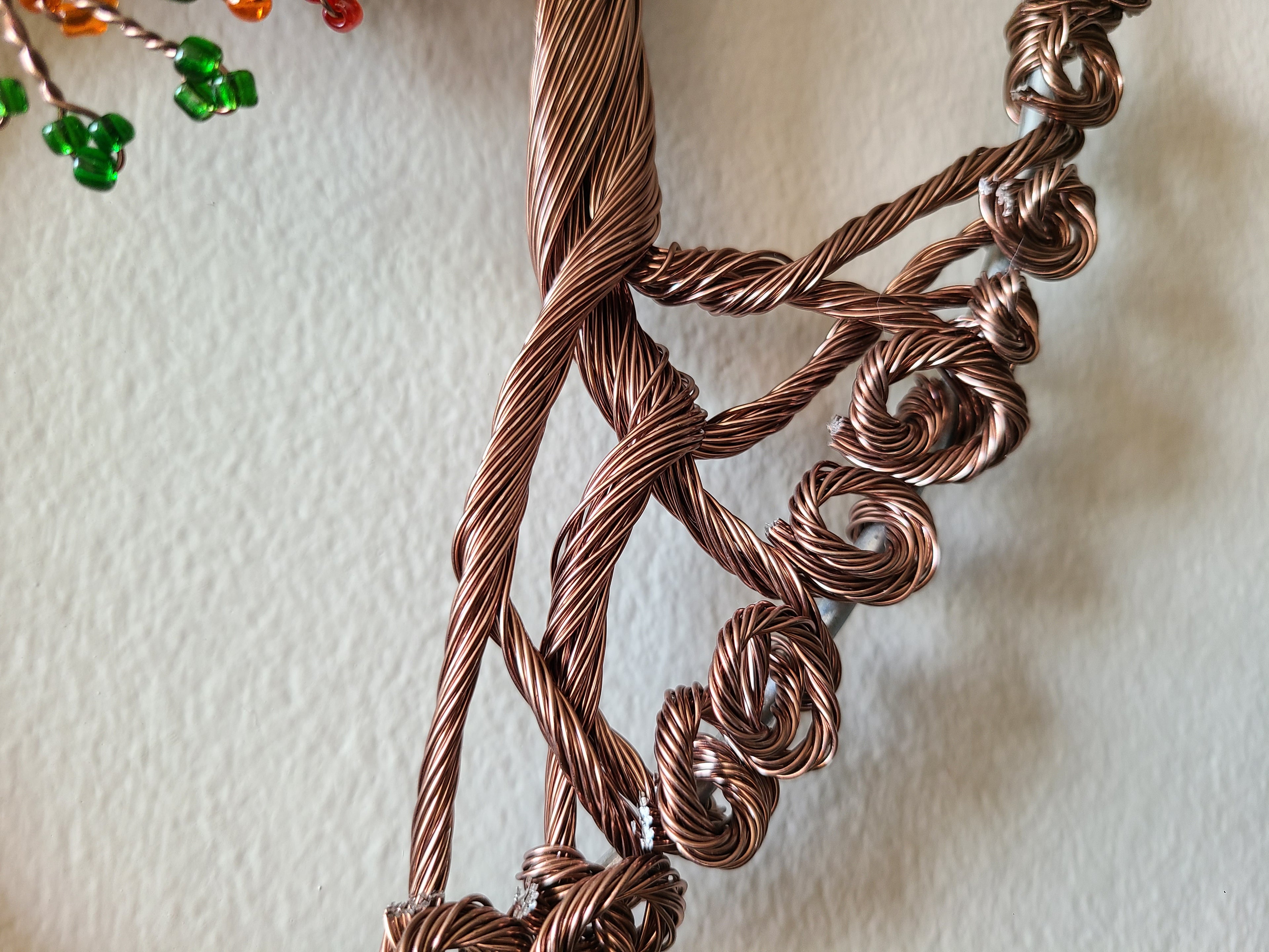 Close-up of a braided copper necklace on a textured beige background