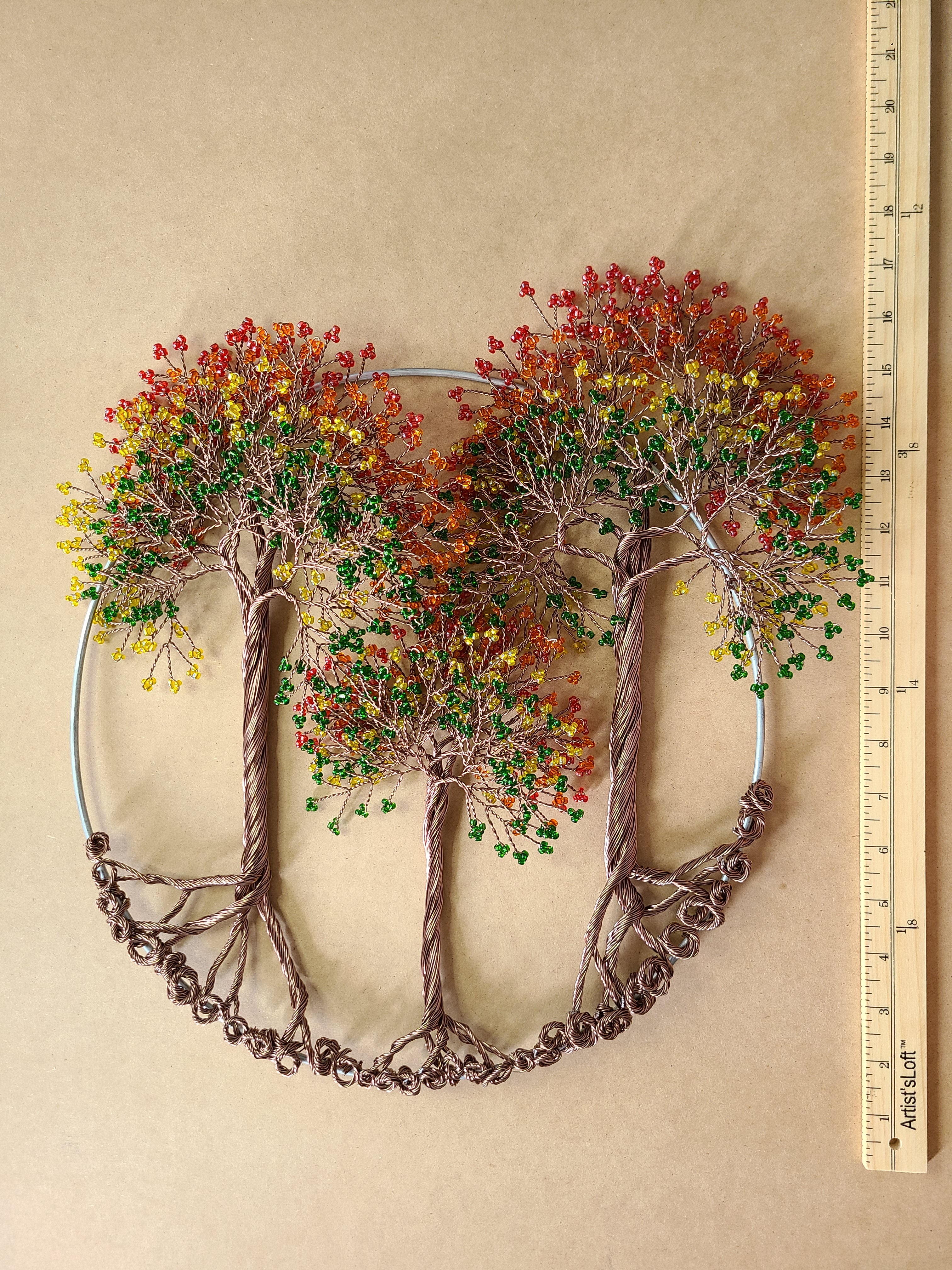 Decorative wall art with tree branches and autumn leaves on a beige background, accompanied by a ruler for scale.