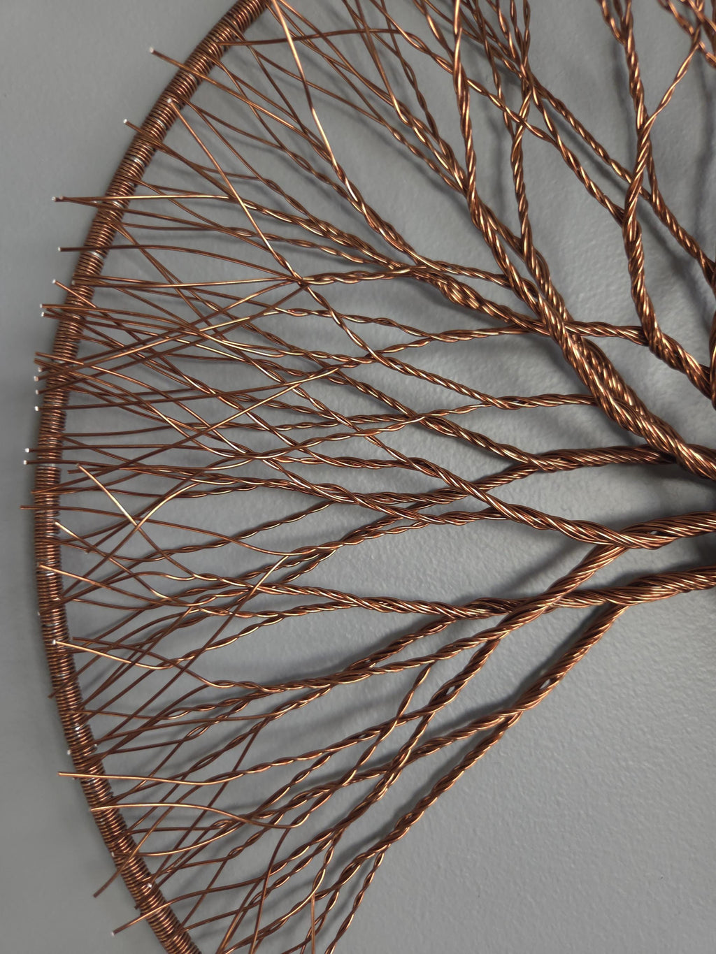 Copper wire tree sculpture on a gray background