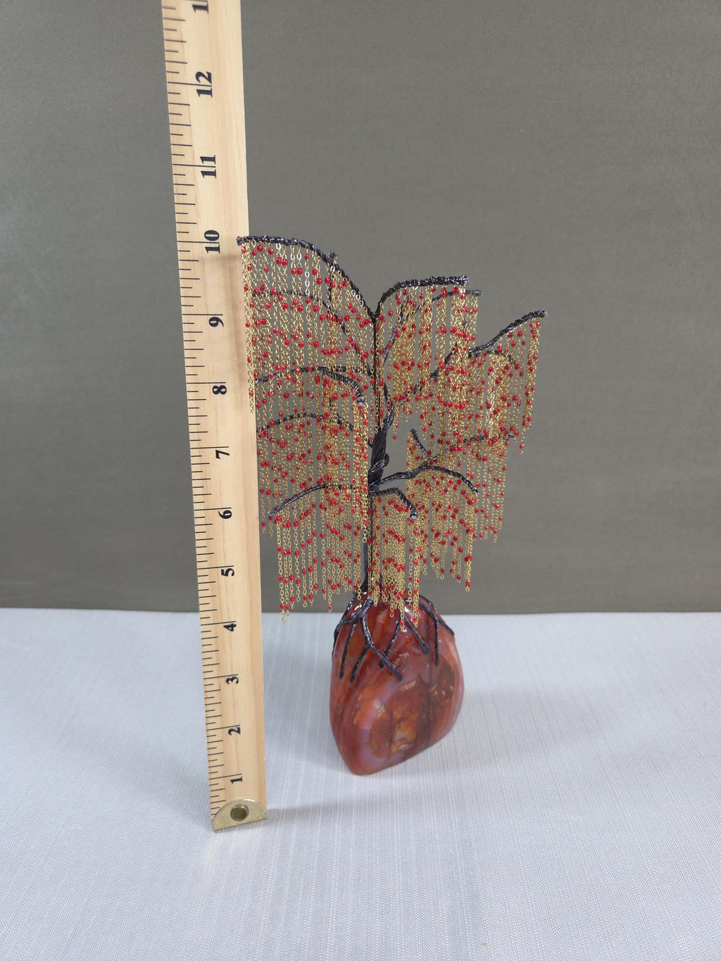 Decorative item with a tree design on a heart base next to a ruler for scale.