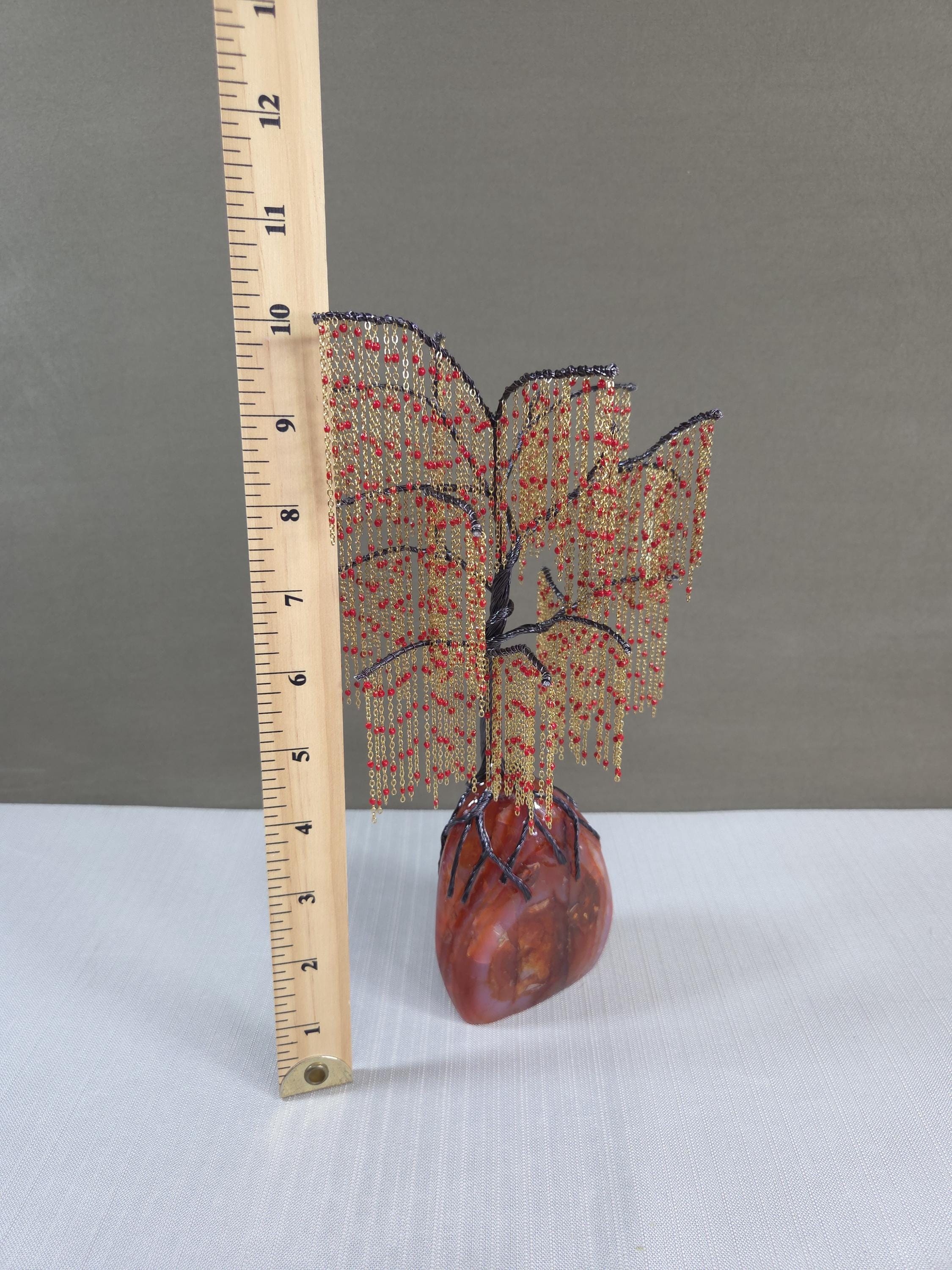 Decorative item with a tree design on a heart base next to a ruler for scale.