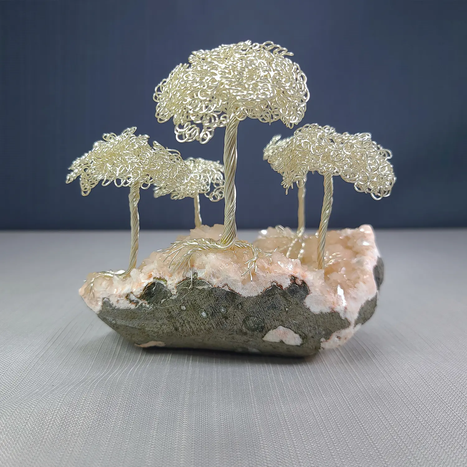 Wire tree sculpture on a rock with a dark blue background